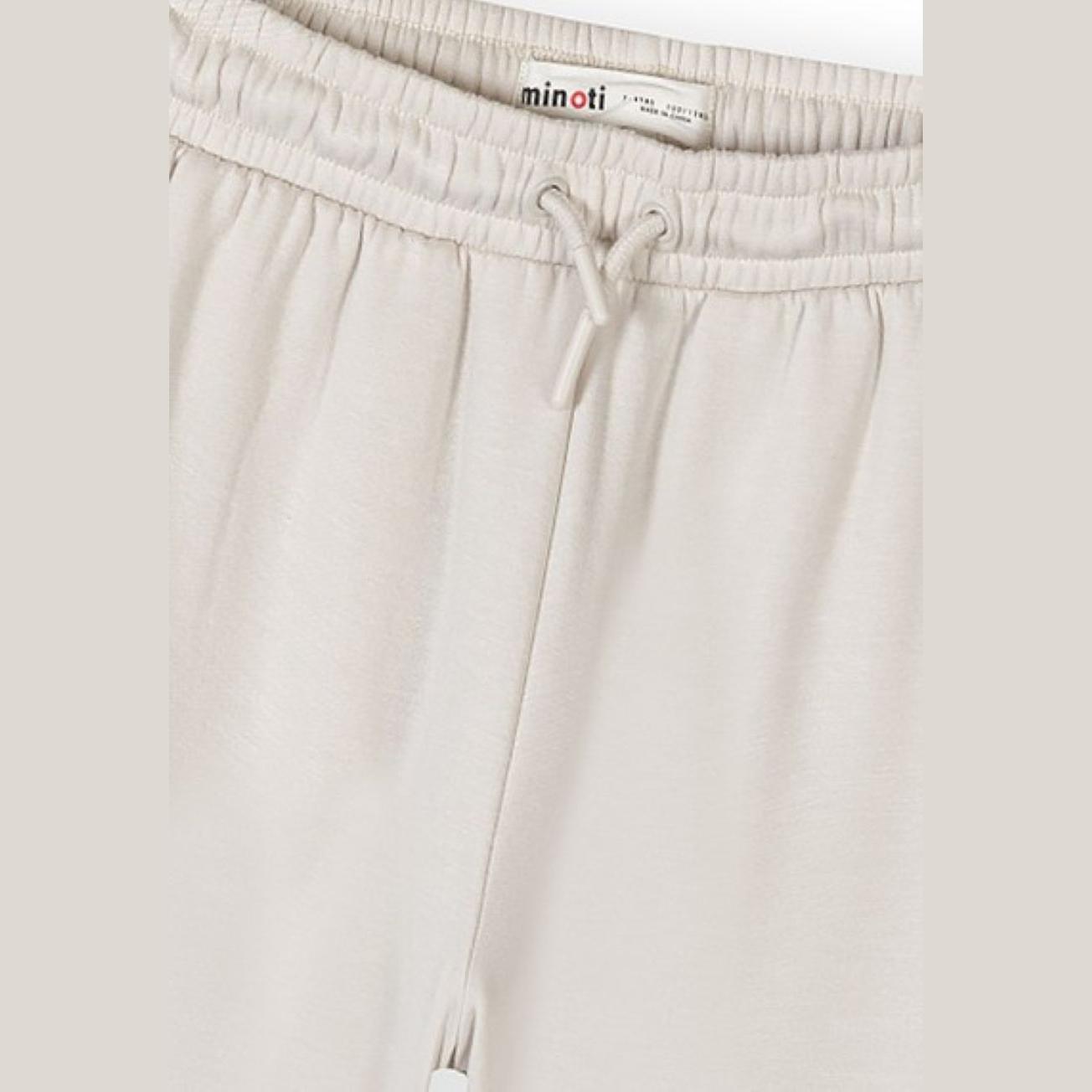 Close-up detail of elasticated waistband with white drawstring and Minoti label on off-white joggers