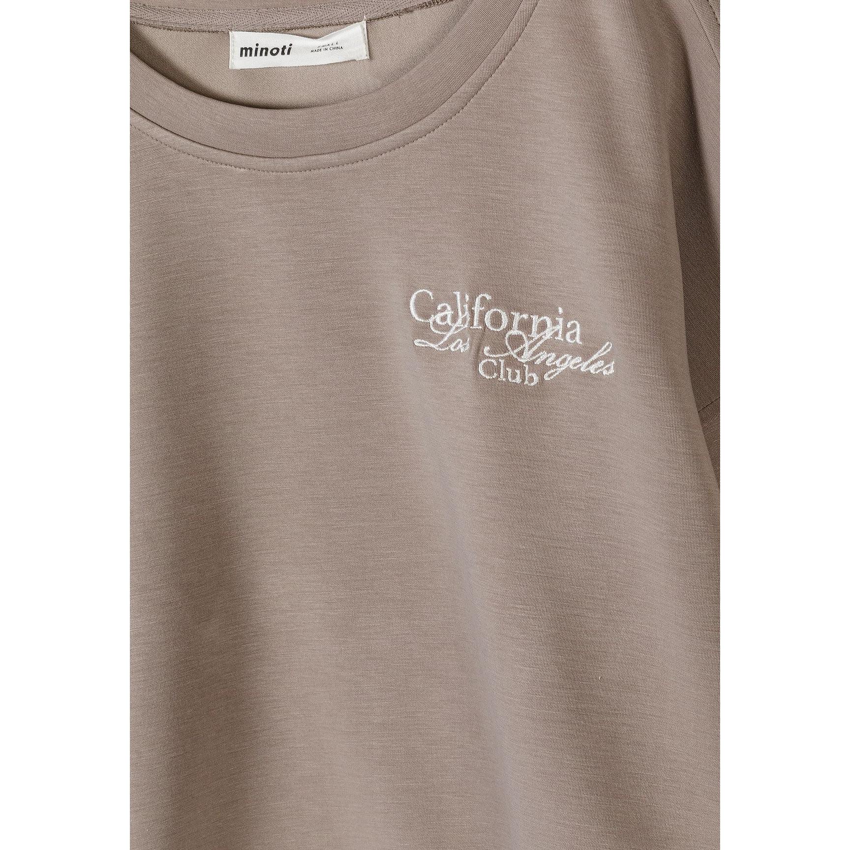 Close-up detail of Minoti label and California Los Angeles Club embroidery on brown sweatshirt fabric