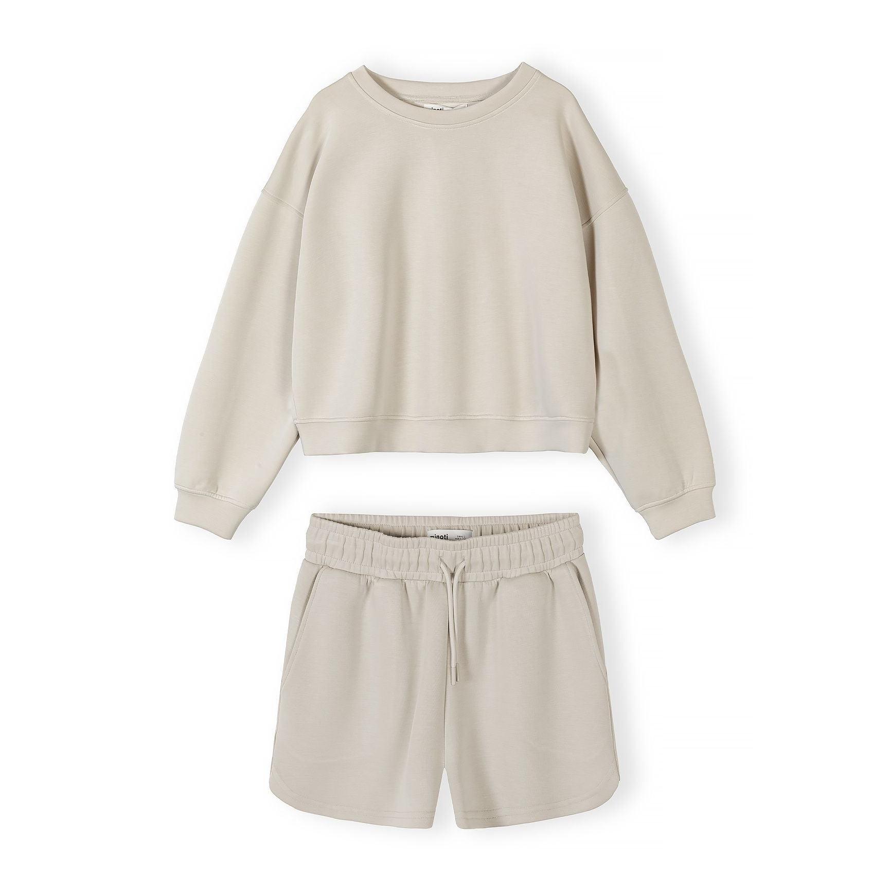 Beige sweatshirt and shorts set laid flat on white background showing coordinated loungewear pieces