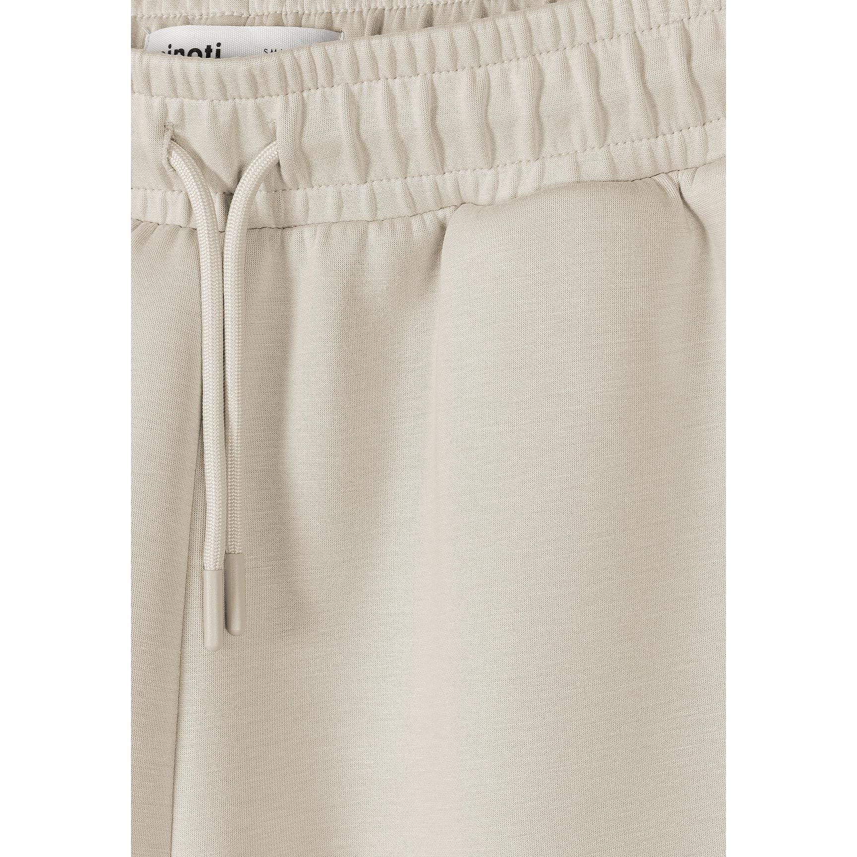 Detail shot of beige shorts waistband and pocket construction with Minoti label visible