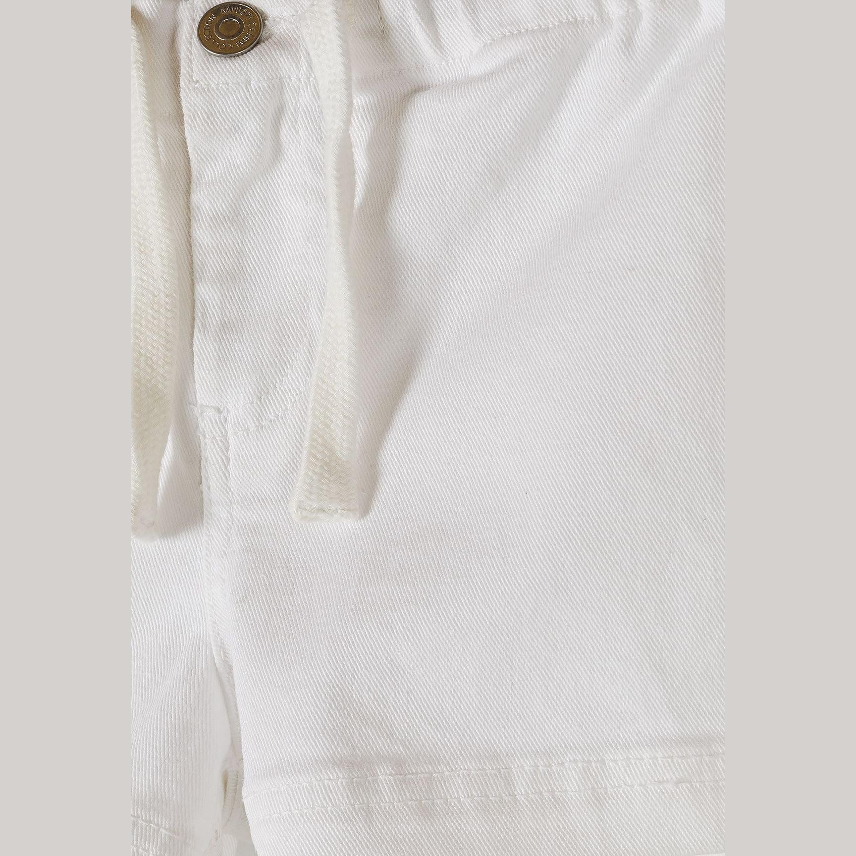 Close-up detail of white twill shorts showing button fastening, drawstring ties and fabric texture against neutral background