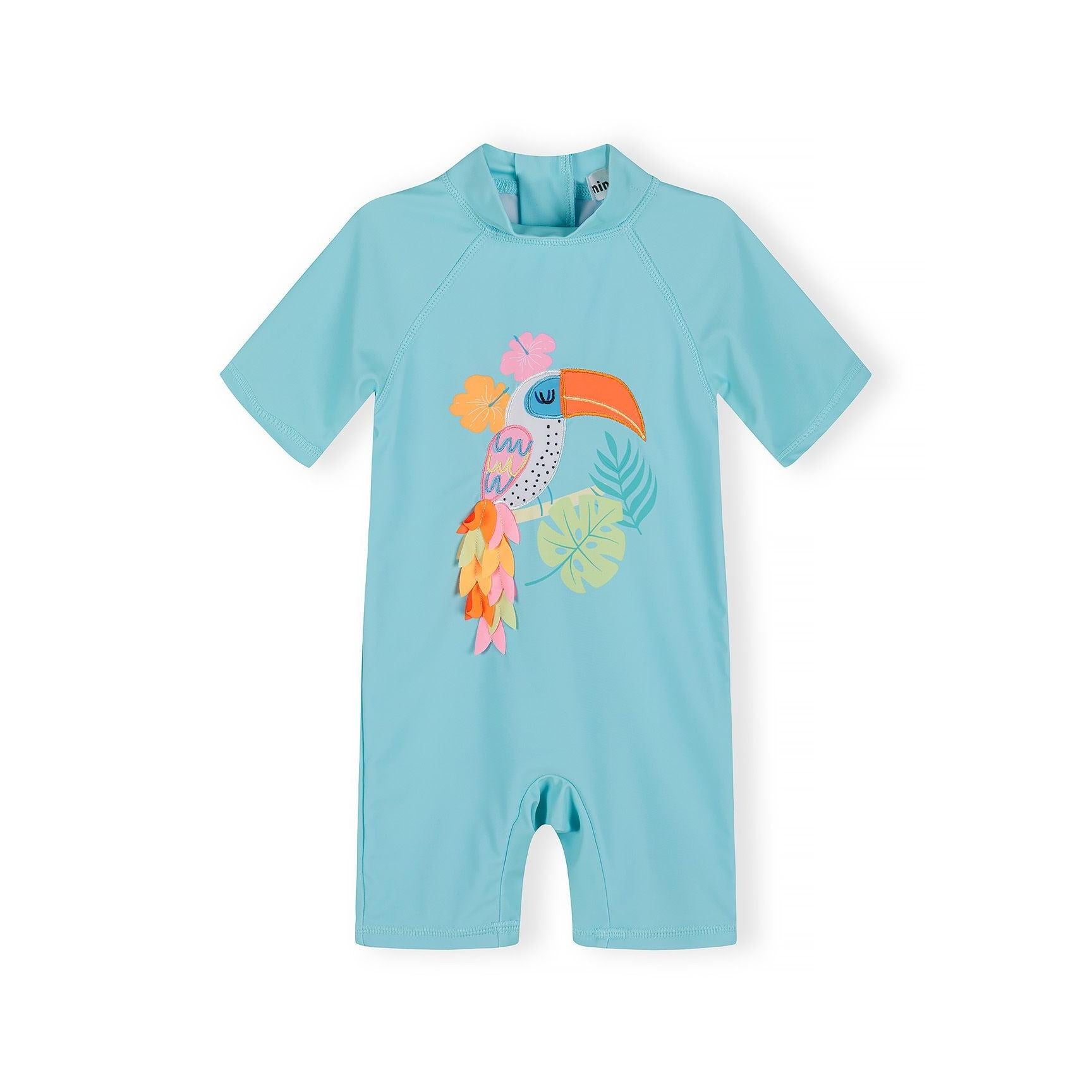 Close-up detail of tucan applique design showing tropical bird with orange beak surrounded by hibiscus flowers and palm leaves