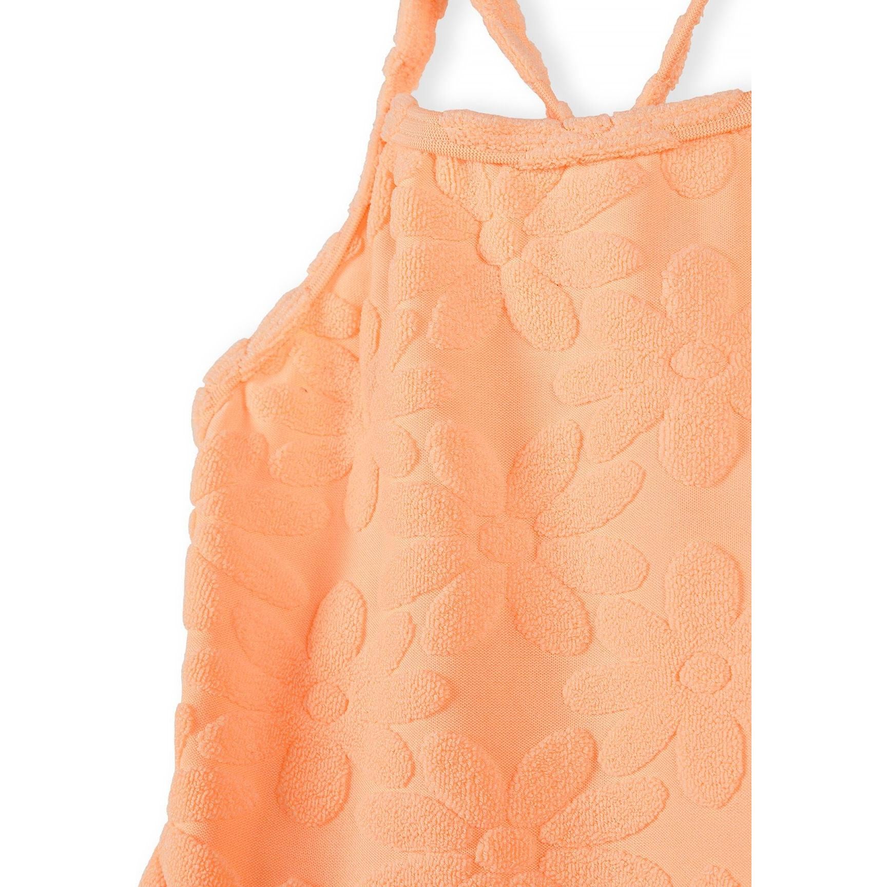 Close-up detail of neon orange jacquard fabric showing raised circular textured pattern and shoulder strap construction