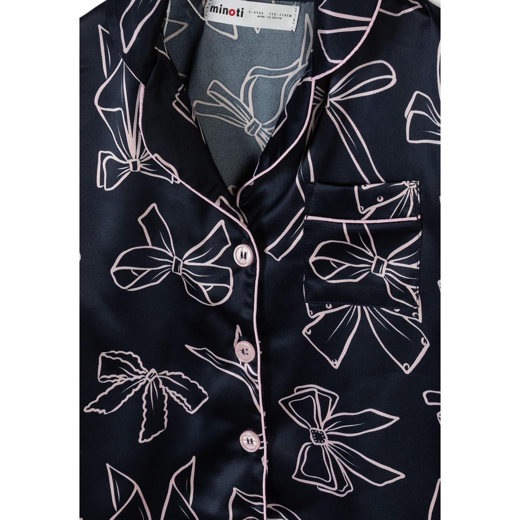 Detail view of navy satin pyjama top showing lapel collar, button placket, chest pocket and bow print pattern with Minoti label visible