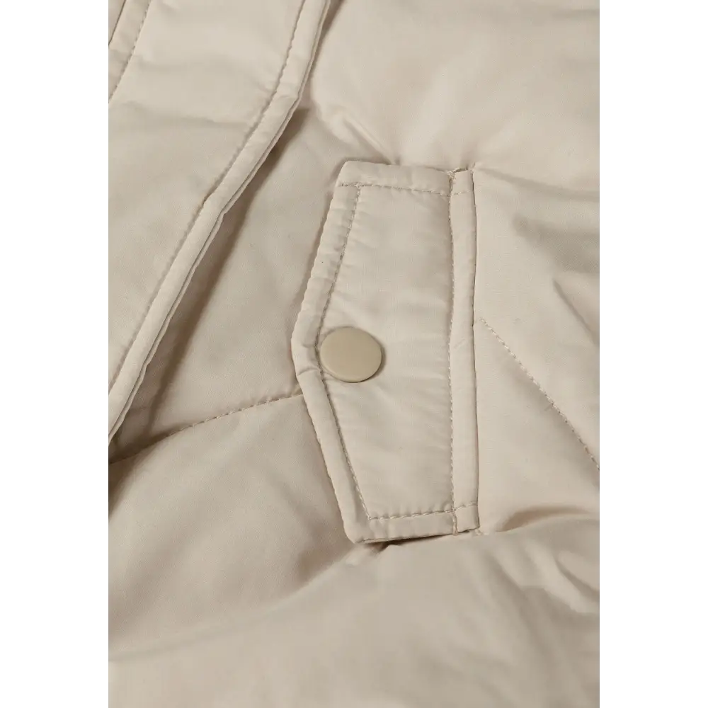 Detail view of cream snowsuit interior showing zip closure, snap buttons, quilted padding and fleece lining construction