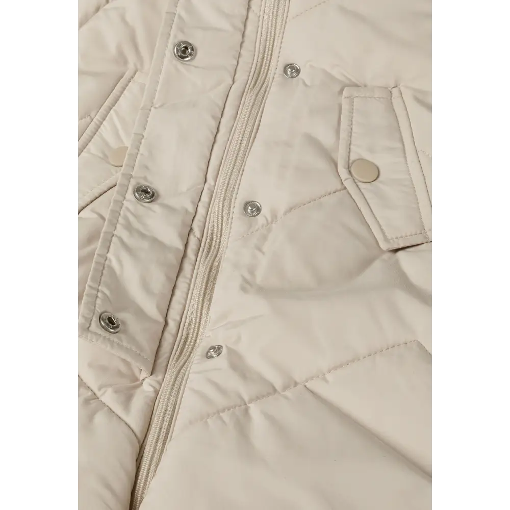 Detail view of cream snowsuit interior showing zip closure, snap buttons, quilted padding and fleece lining construction