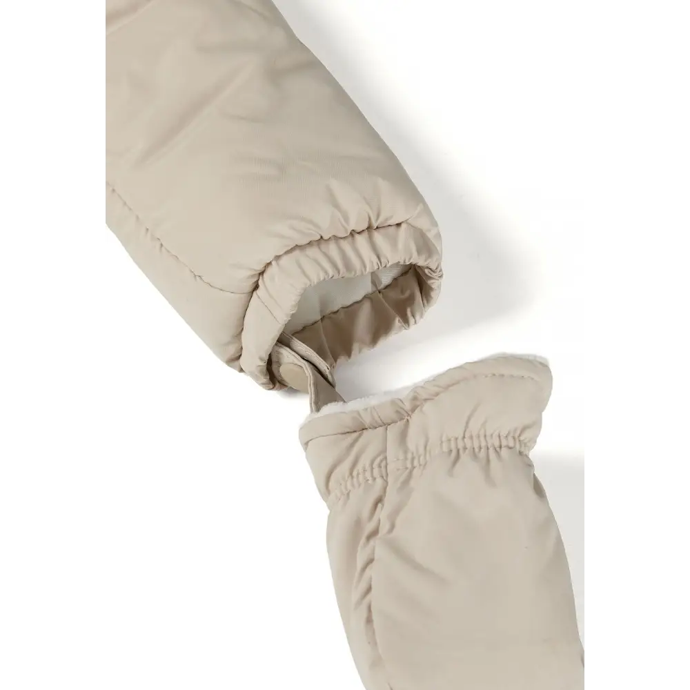 Detail view of cream snowsuit interior showing zip closure, snap buttons, quilted padding and fleece lining construction