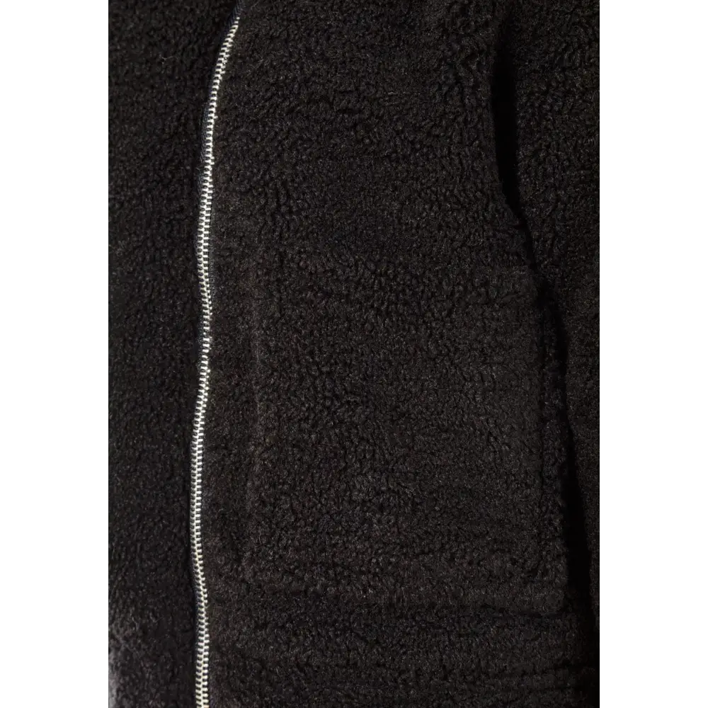 Close-up detail of black teddy borg jacket showing textured fleece fabric and silver zip fastening