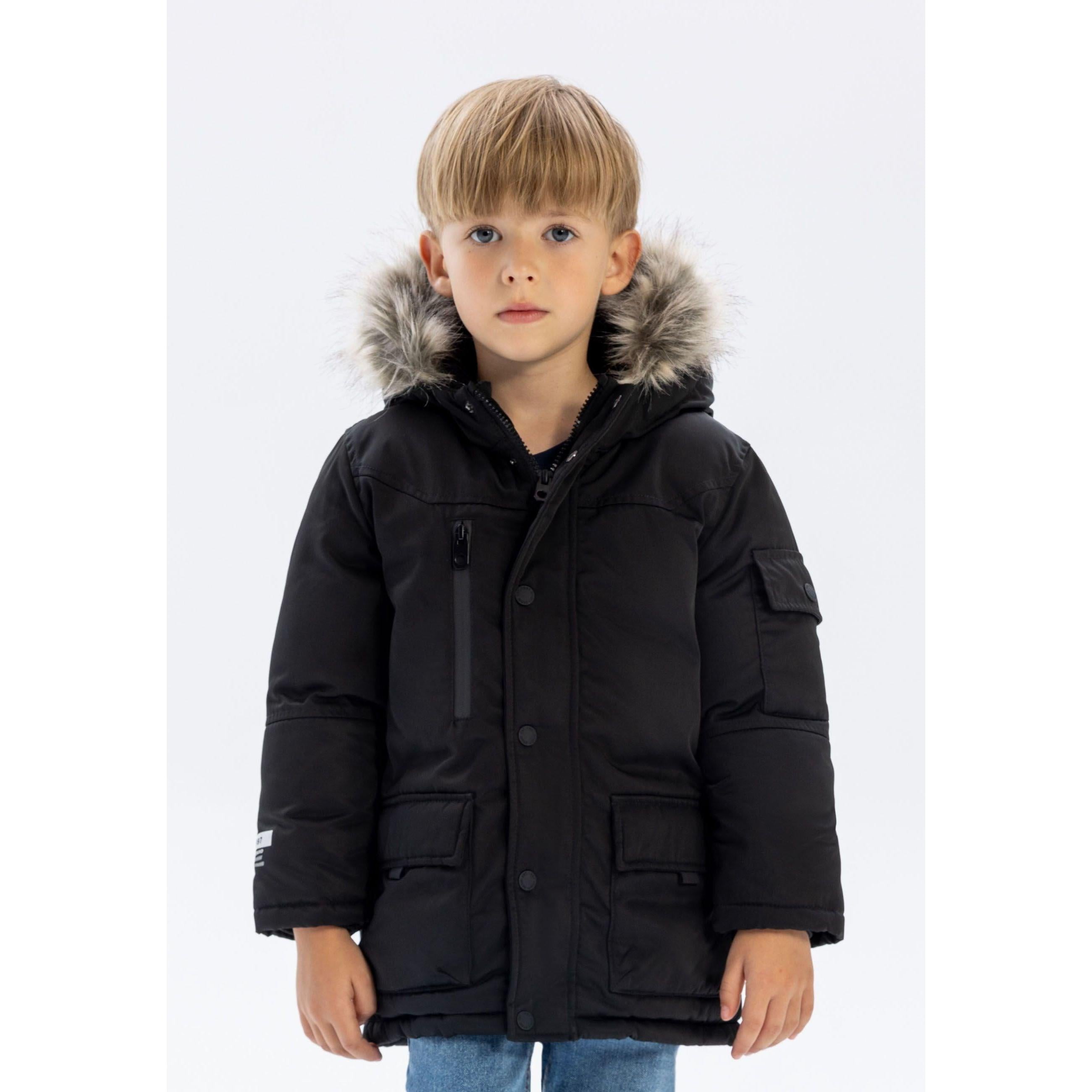Same young boy in black long parka with faux fur hood, slightly different angle showing full silhouette