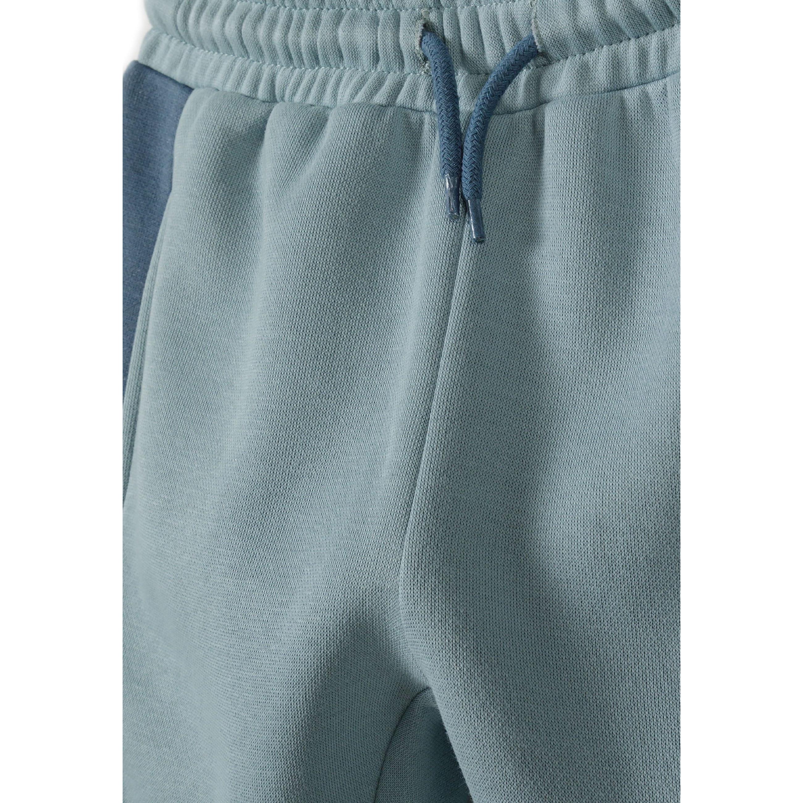 Close-up detail of blue joggers showing drawstring waistband and soft fabric texture