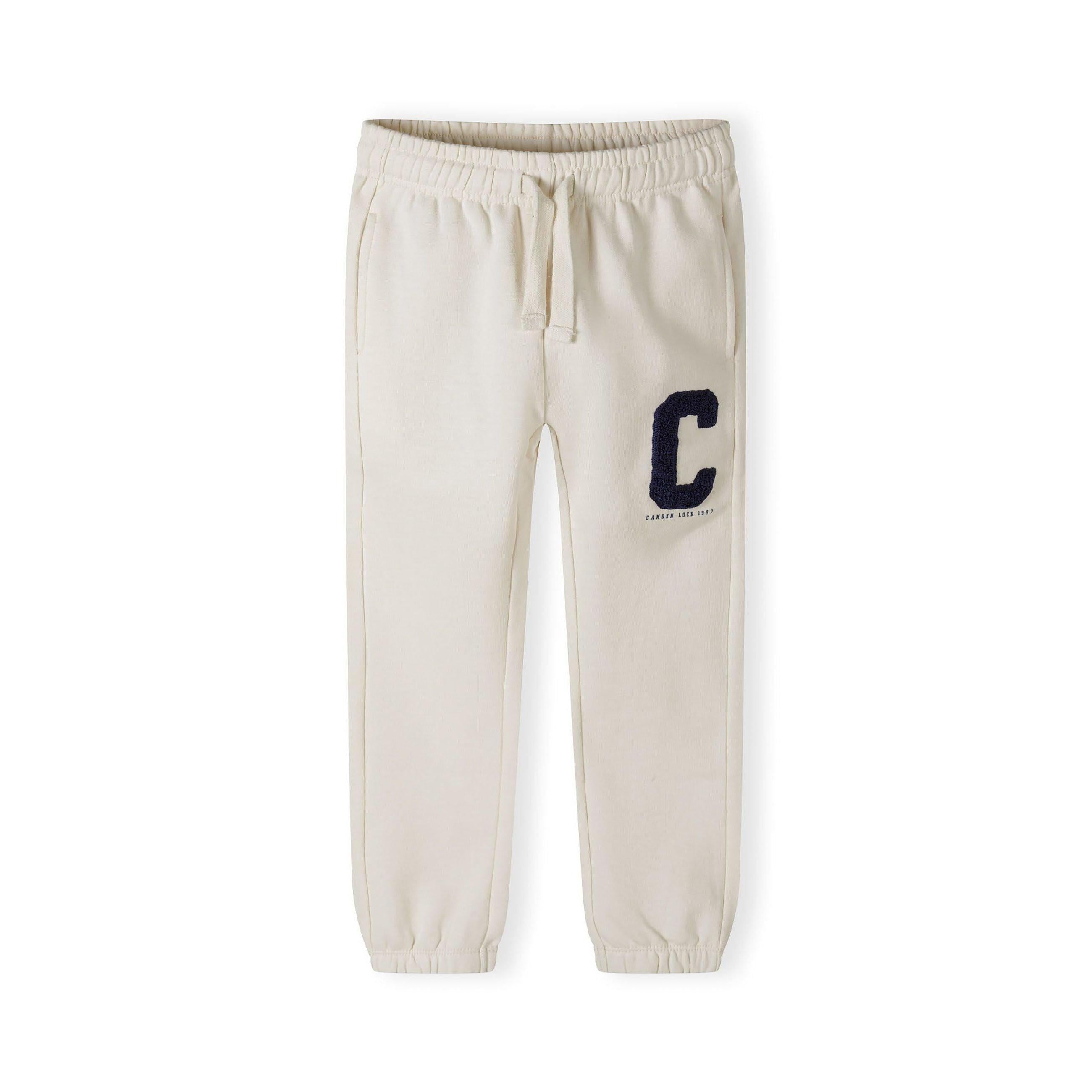 Close-up detail of cream joggers showing large navy blue C boucle embroidery and drawstring waistband
