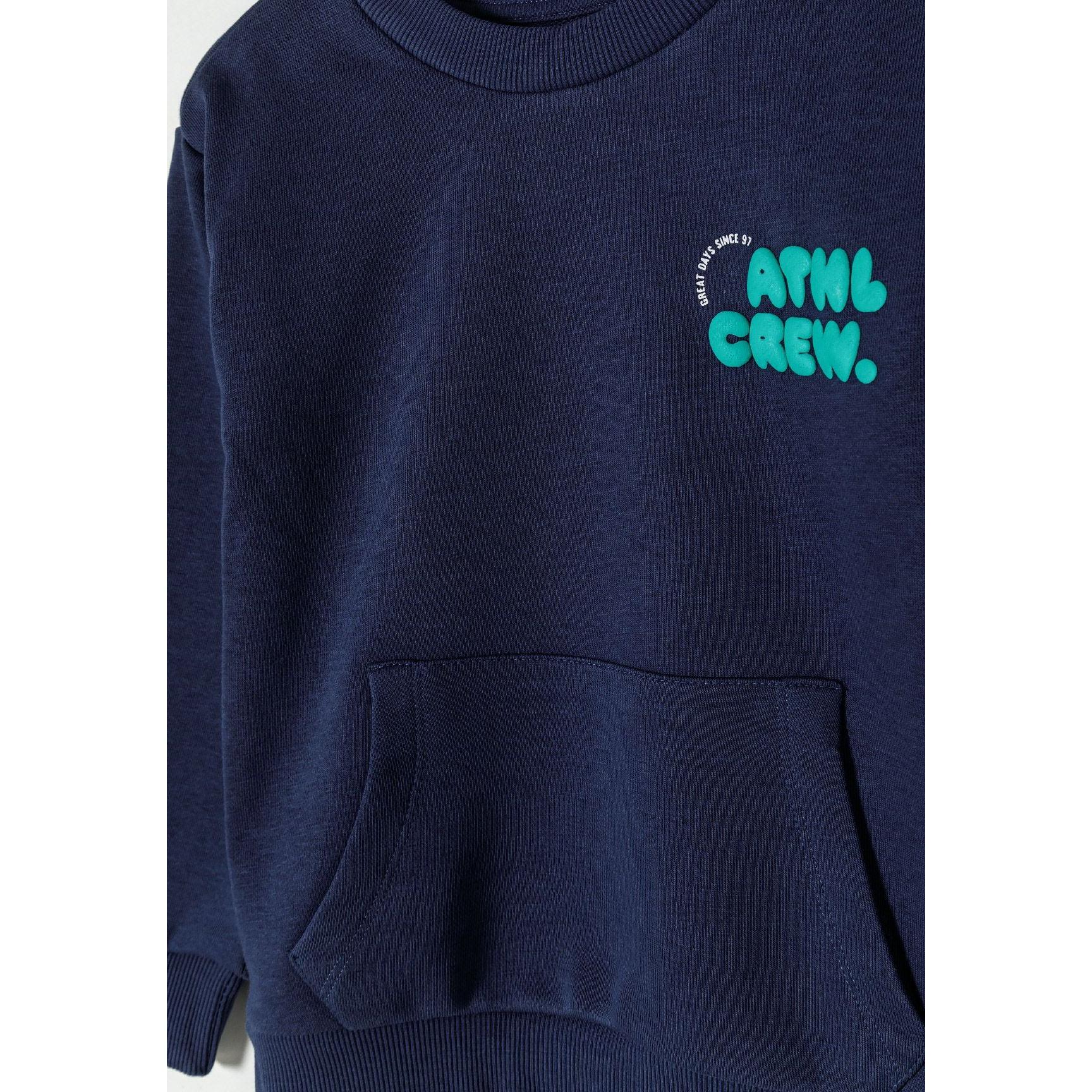 Close-up detail of navy sweatshirt showing ATWL CREW teal text print on chest and kangaroo pocket