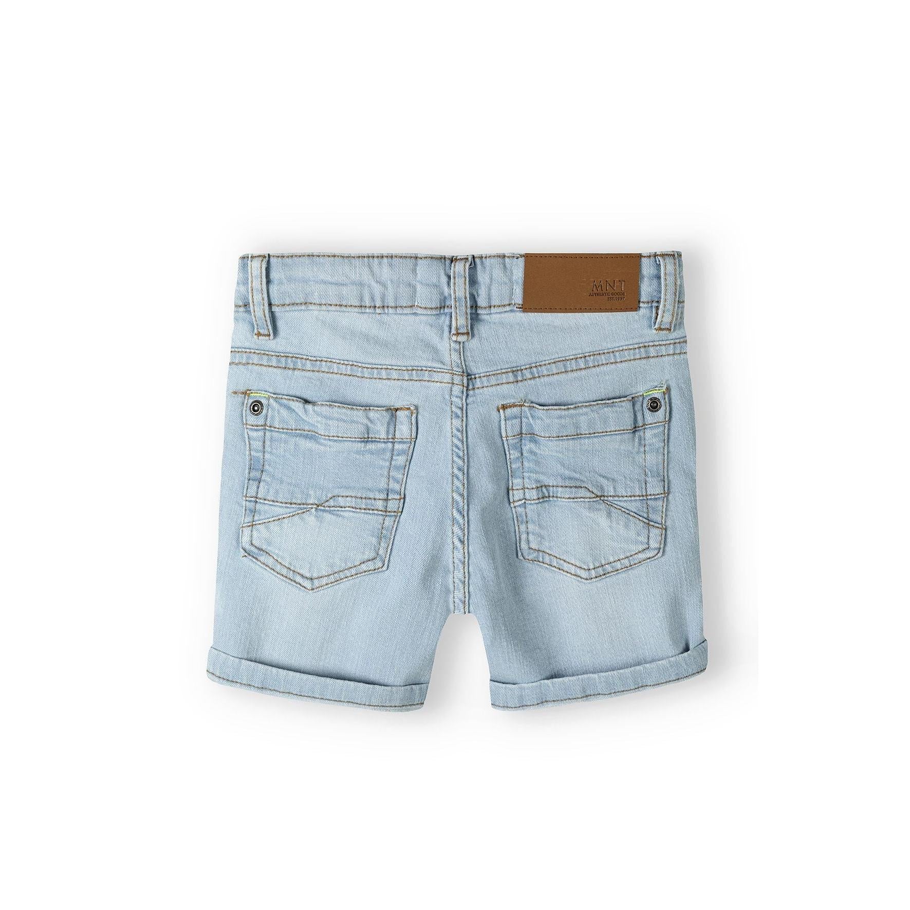 Back view of light blue denim shorts showing rear pockets and brown leather waistband label on white background