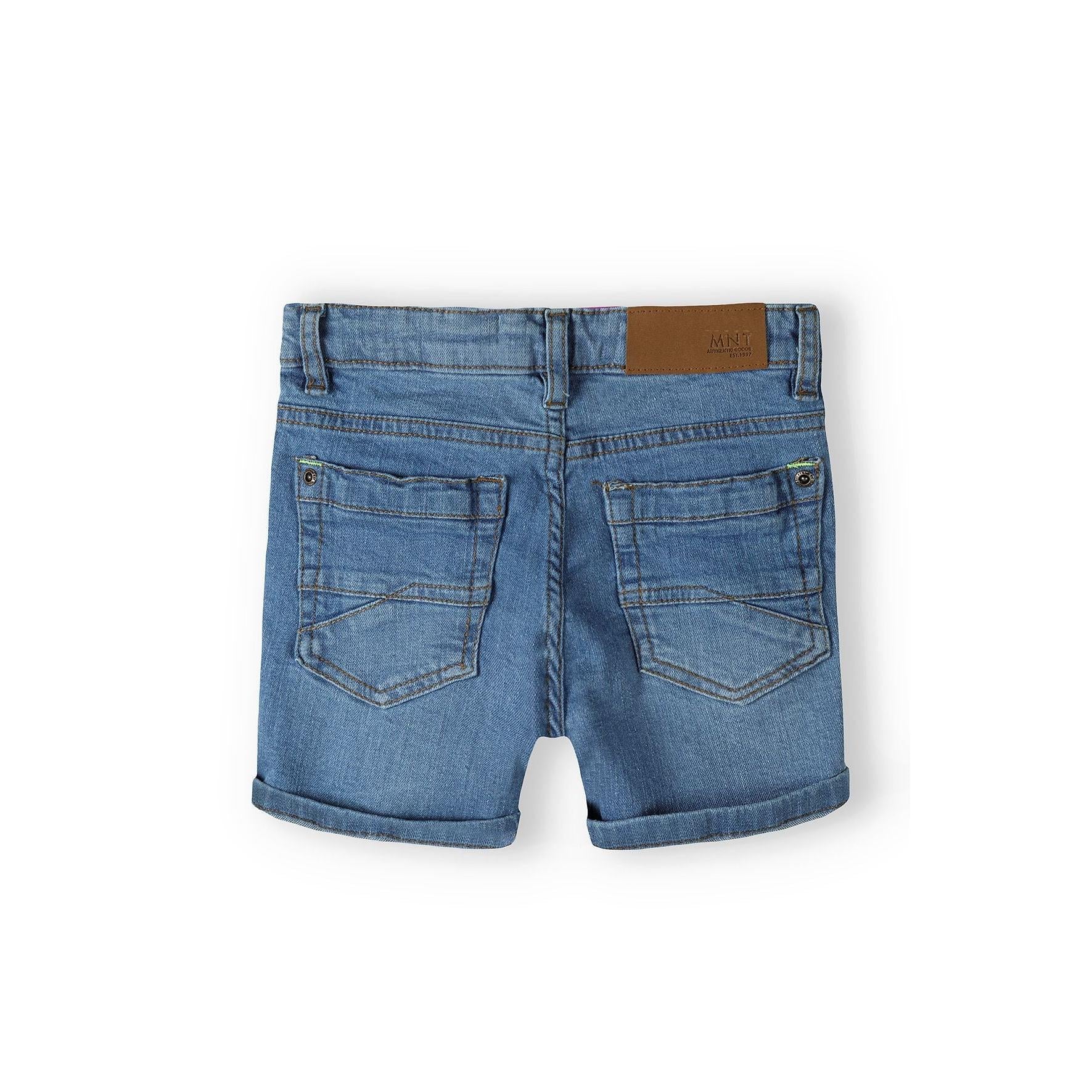 Back view of navy denim shorts showing two back pockets with brown leather Minoti waistband label on white background