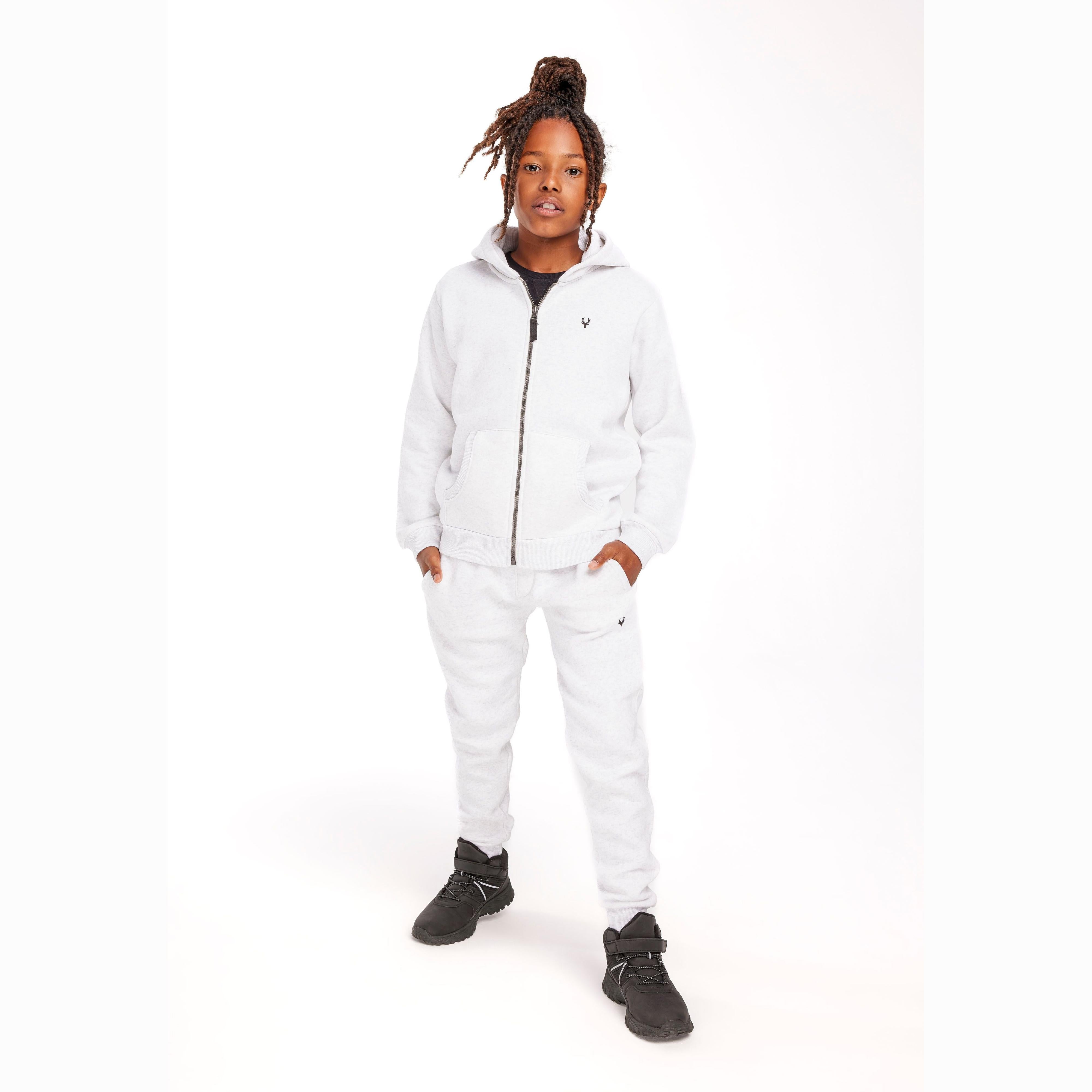 Young person wearing grey joggers and matching hoodie in full length pose against white background