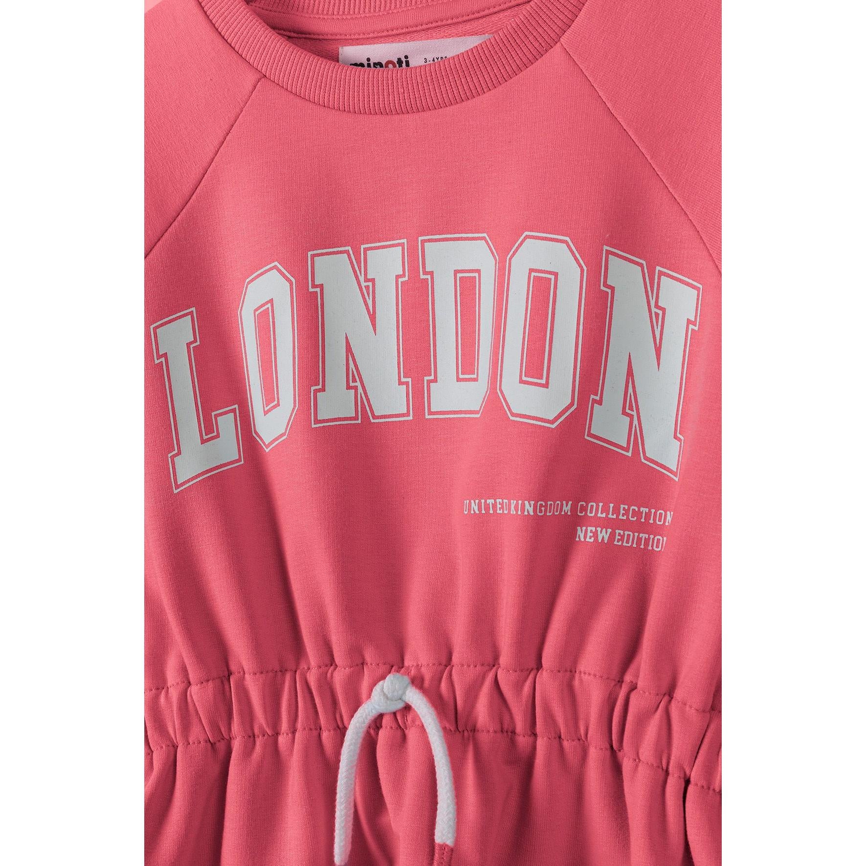 Close-up detail of pink fleece dress showing London print text, elasticated waist with white drawstring