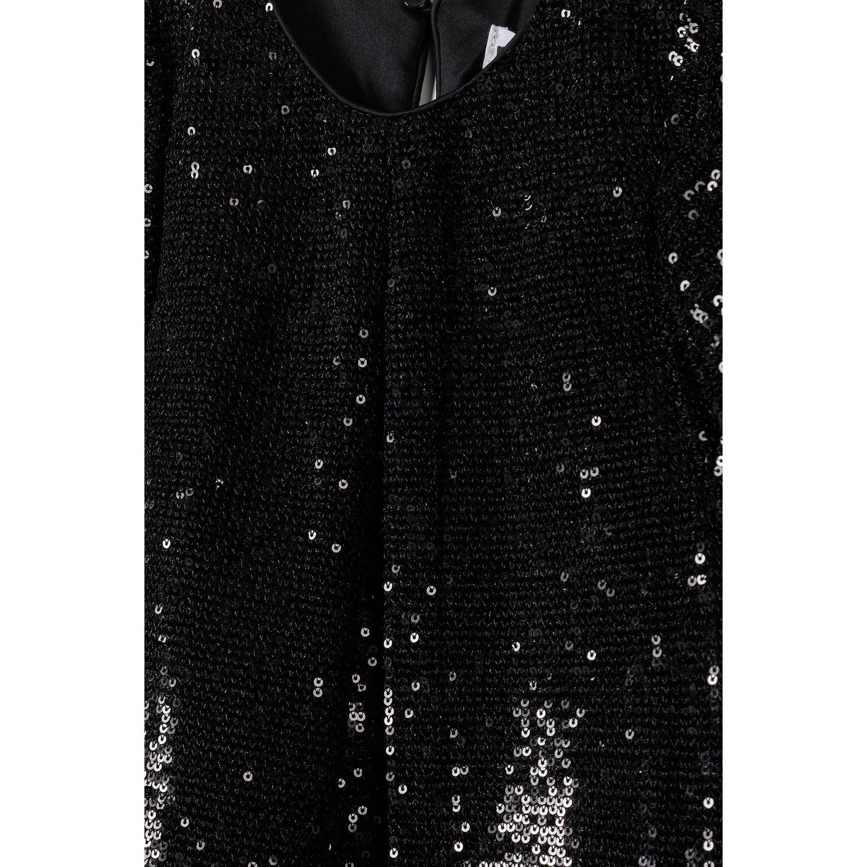Close-up detail of black sequin fabric showing individual sequins and sparkly texture with round neckline visible