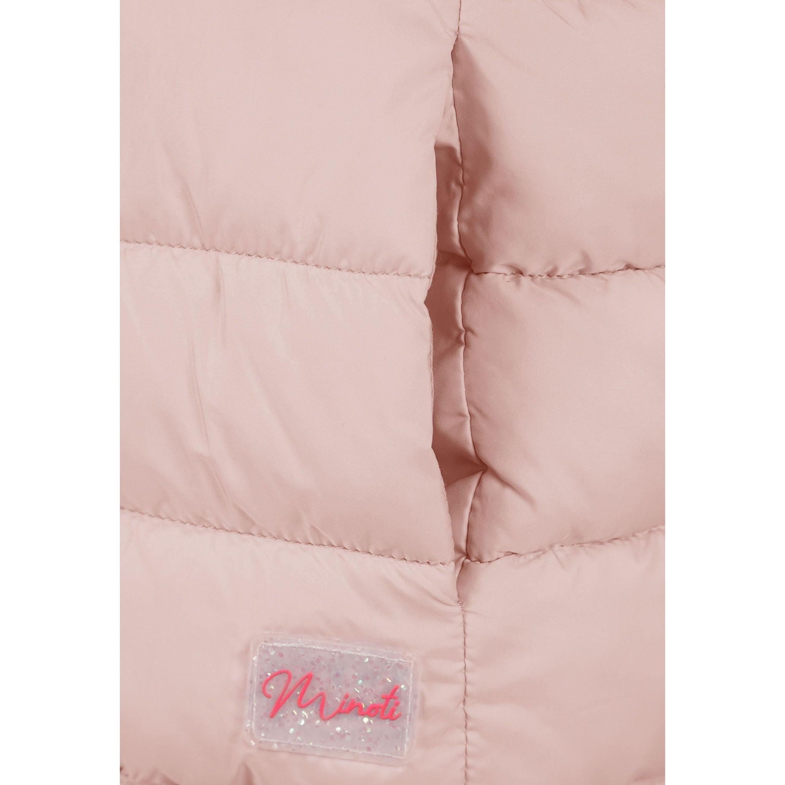Close-up detail of pink quilted fabric showing stitched panels and clear branded patch with pink Minoti logo at bottom hem