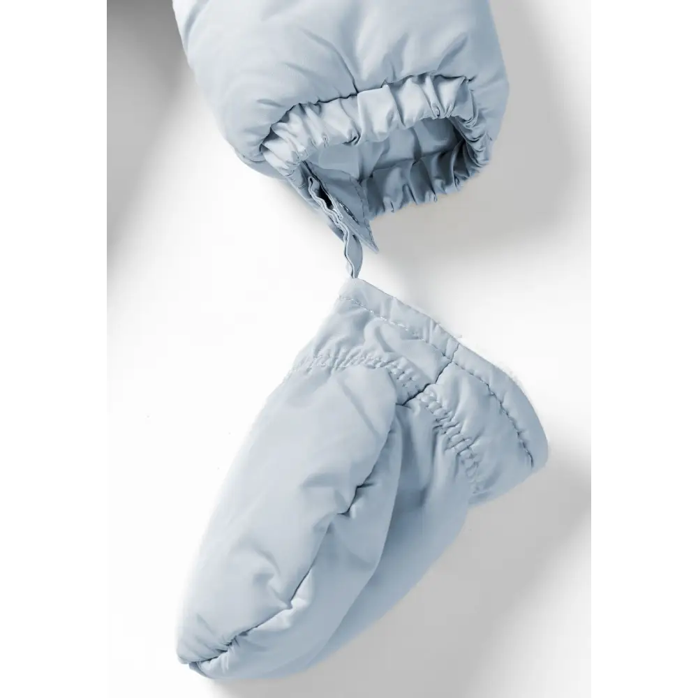 Detail view of light blue snowsuit foot section with elasticated ankle cuff and gathered fabric construction on white background