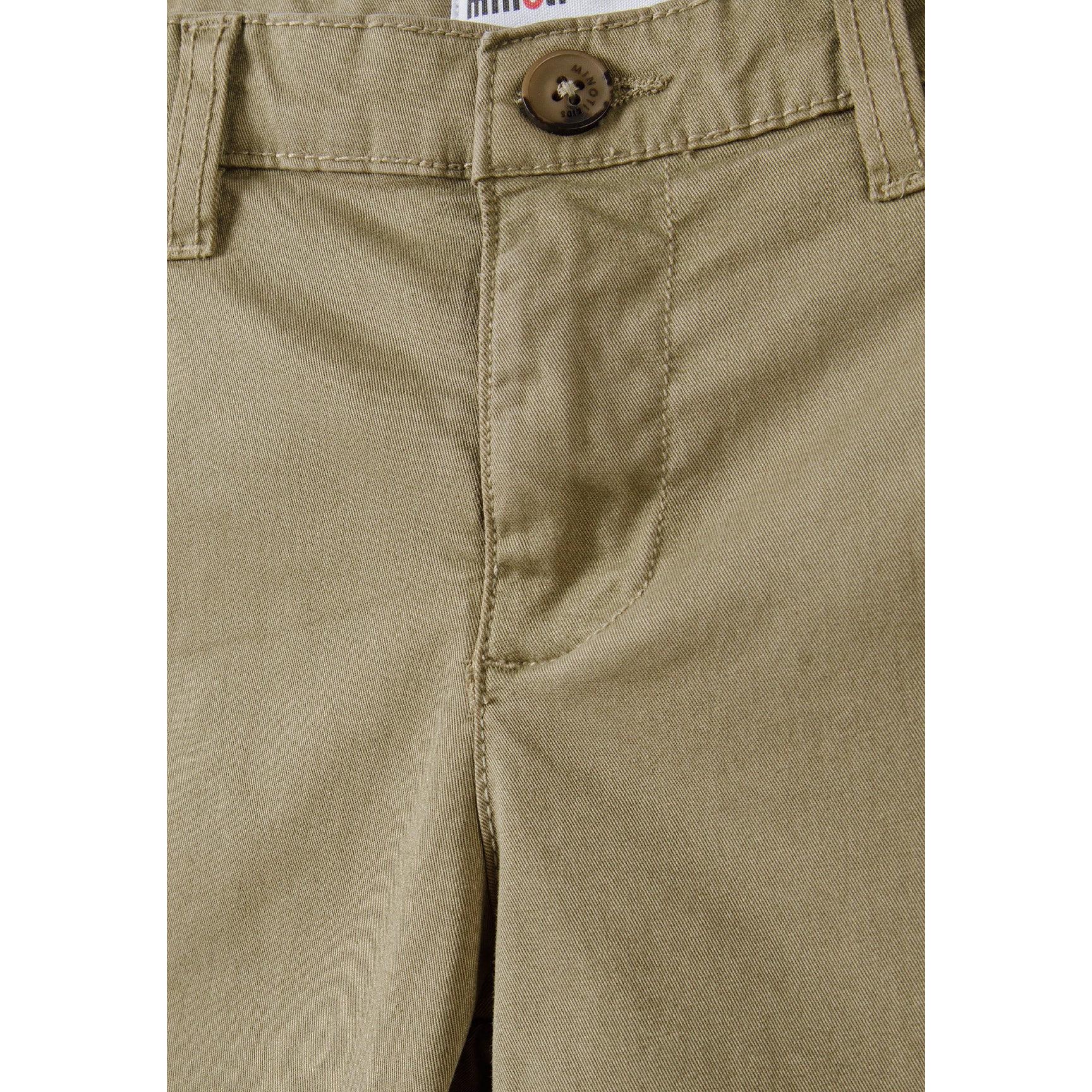 Close-up detail of beige chino shorts waistband showing brown button closure and Minoti label