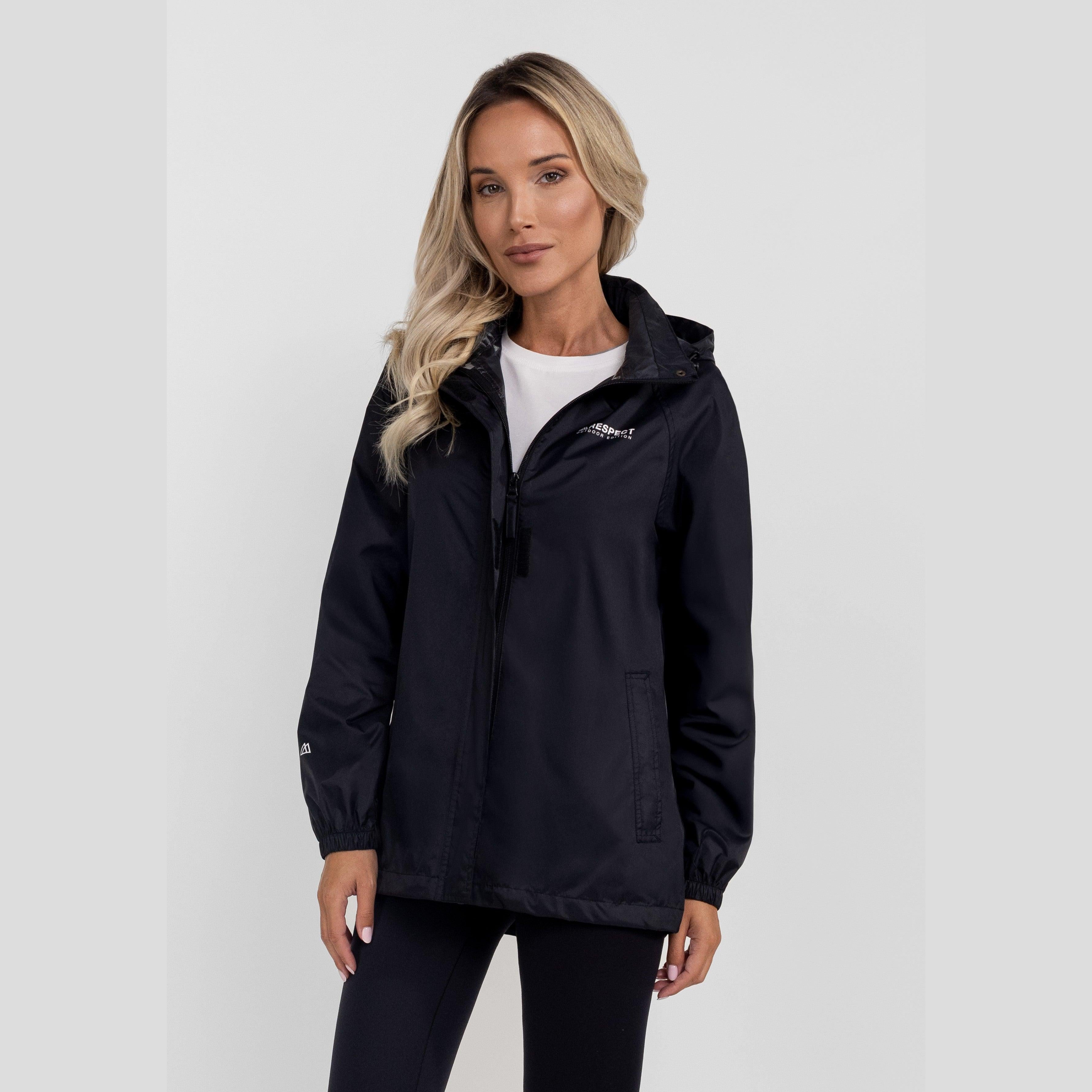 Woman modeling navy blue packaway waterproof jacket with hidden hood, worn over white top against light background