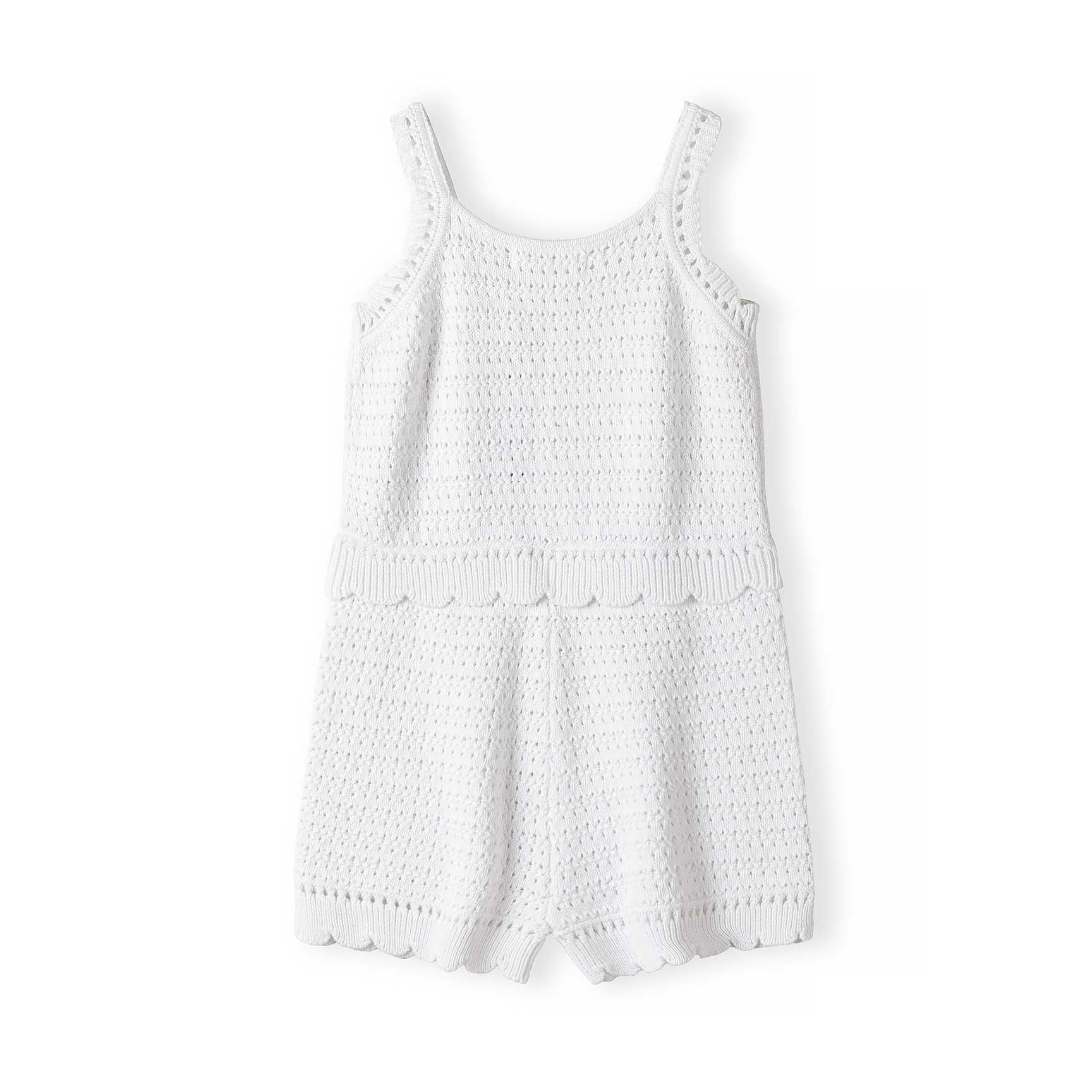 Flat lay of white pointelle knit romper showing decorative openwork pattern, wide shoulder straps, scalloped waistband and hem against white background
