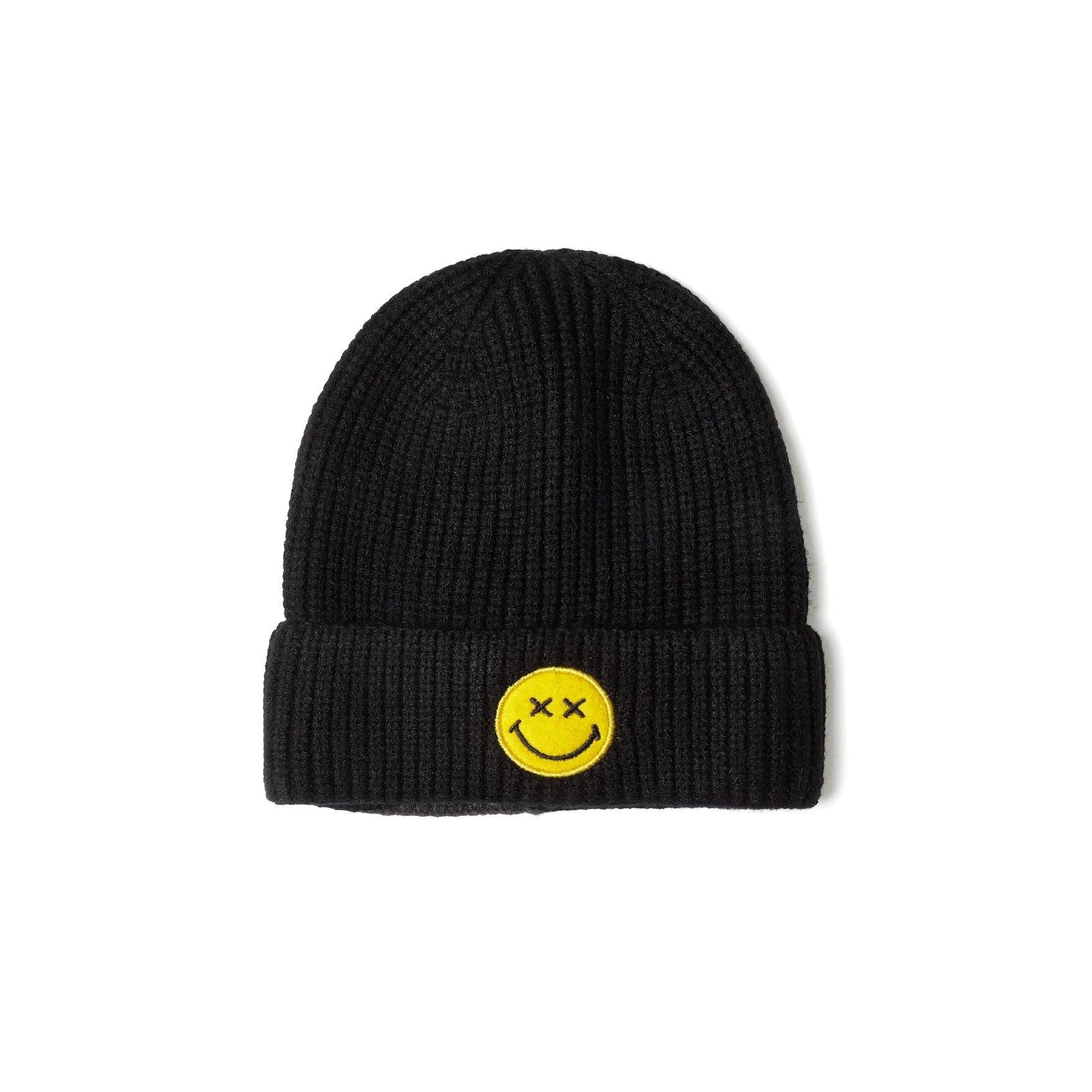 Black ribbed knit beanie with yellow smiley face badge featuring cross eyes, displayed on white background