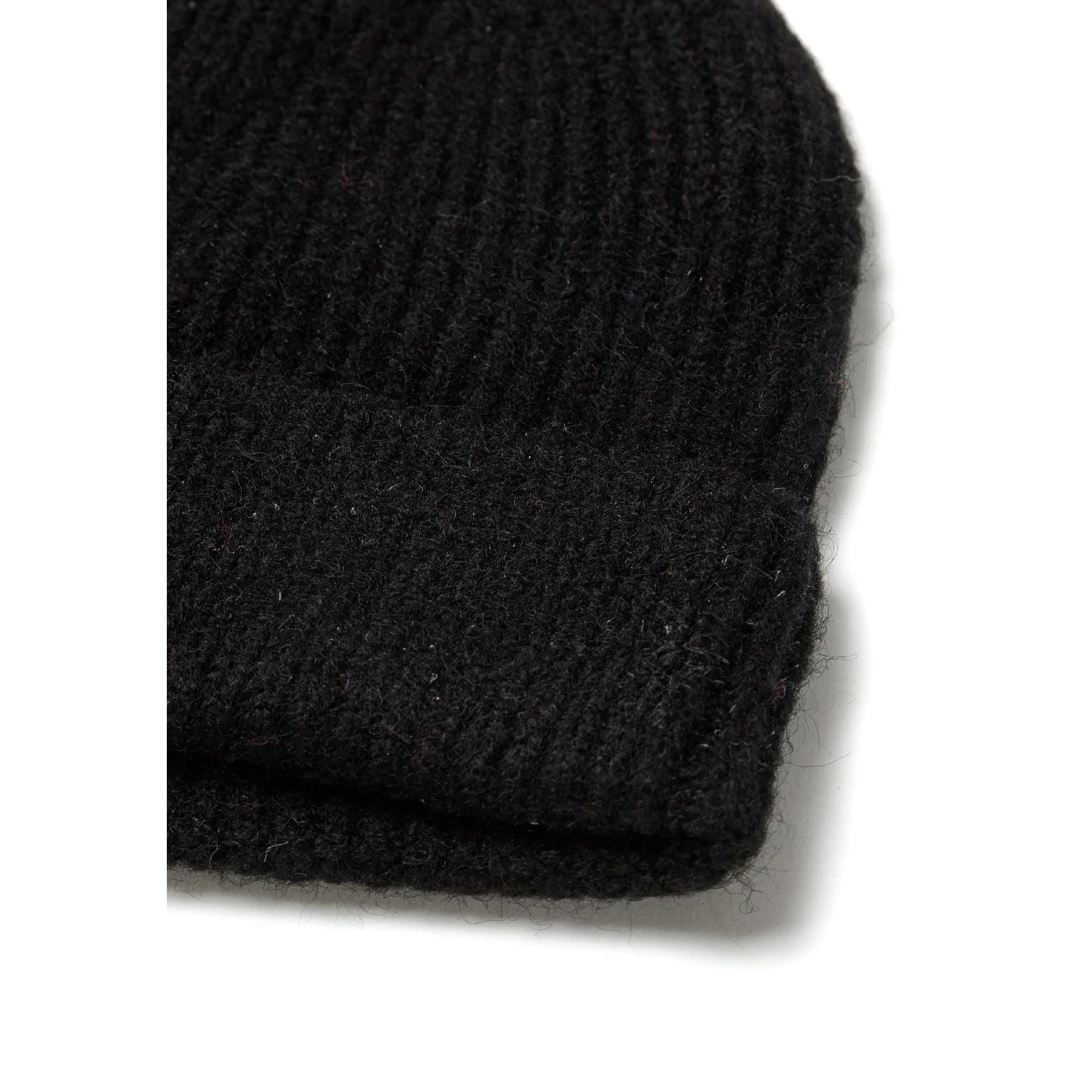 Close-up detail of black beanie showing the ribbed knit texture and folded cuff construction against white background