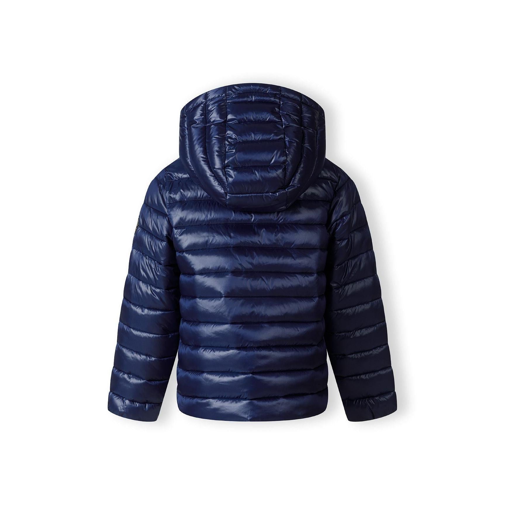 Close-up detail of navy quilted jacket showing circular embroidered badge with heart design and text on padded sleeve