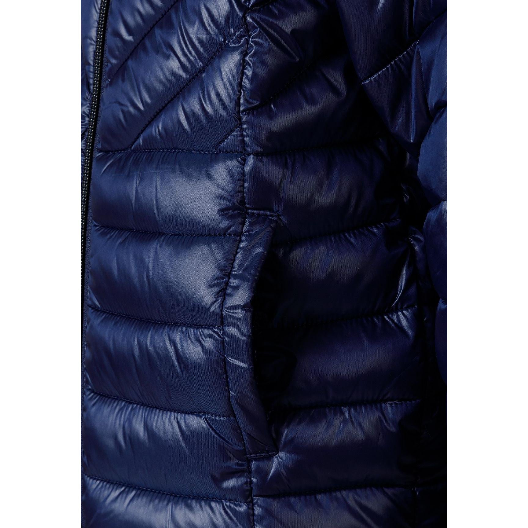 Close-up detail of navy quilted jacket showing circular embroidered badge with heart design and text on padded sleeve