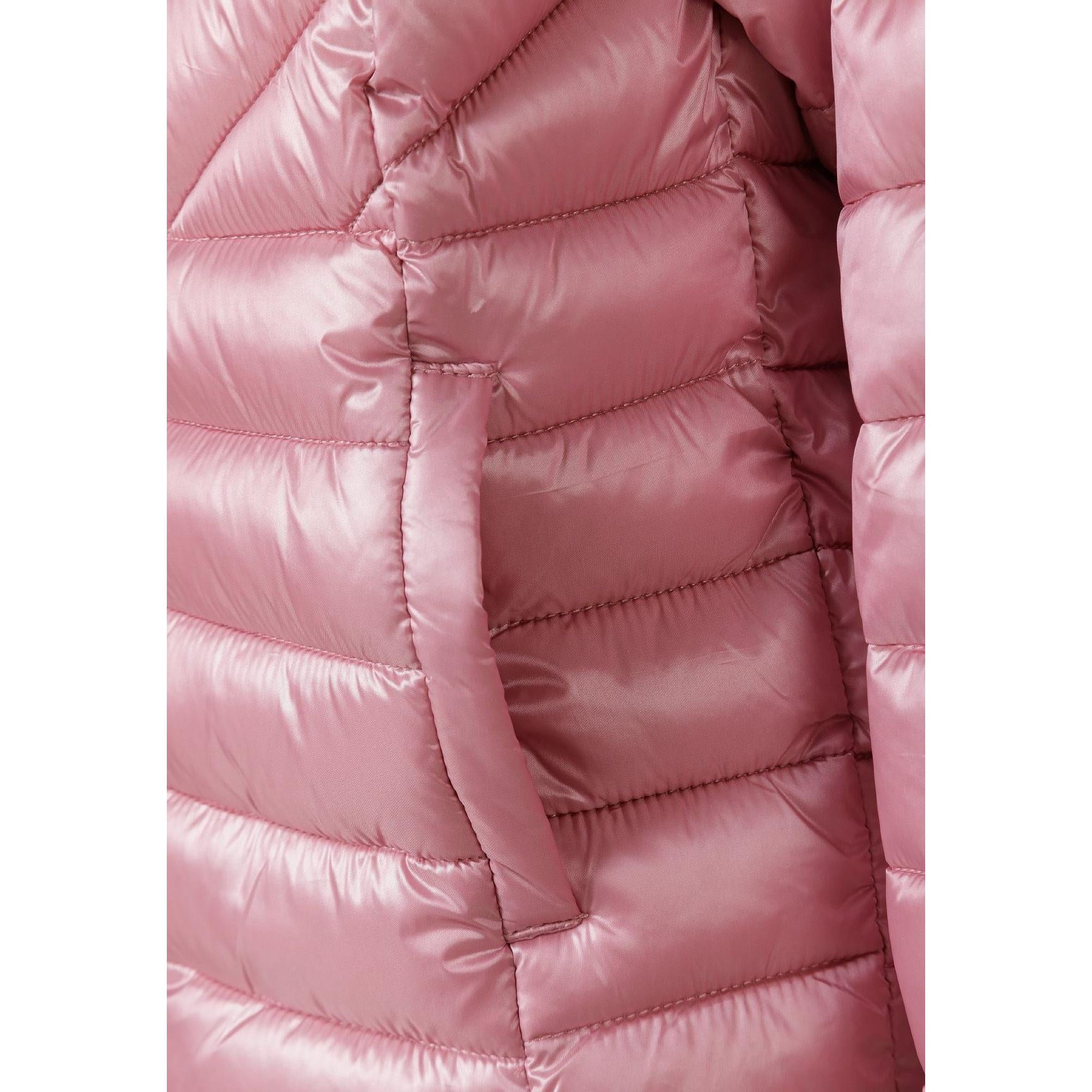Close-up detail of circular embroidered heart badge on pink quilted jacket sleeve