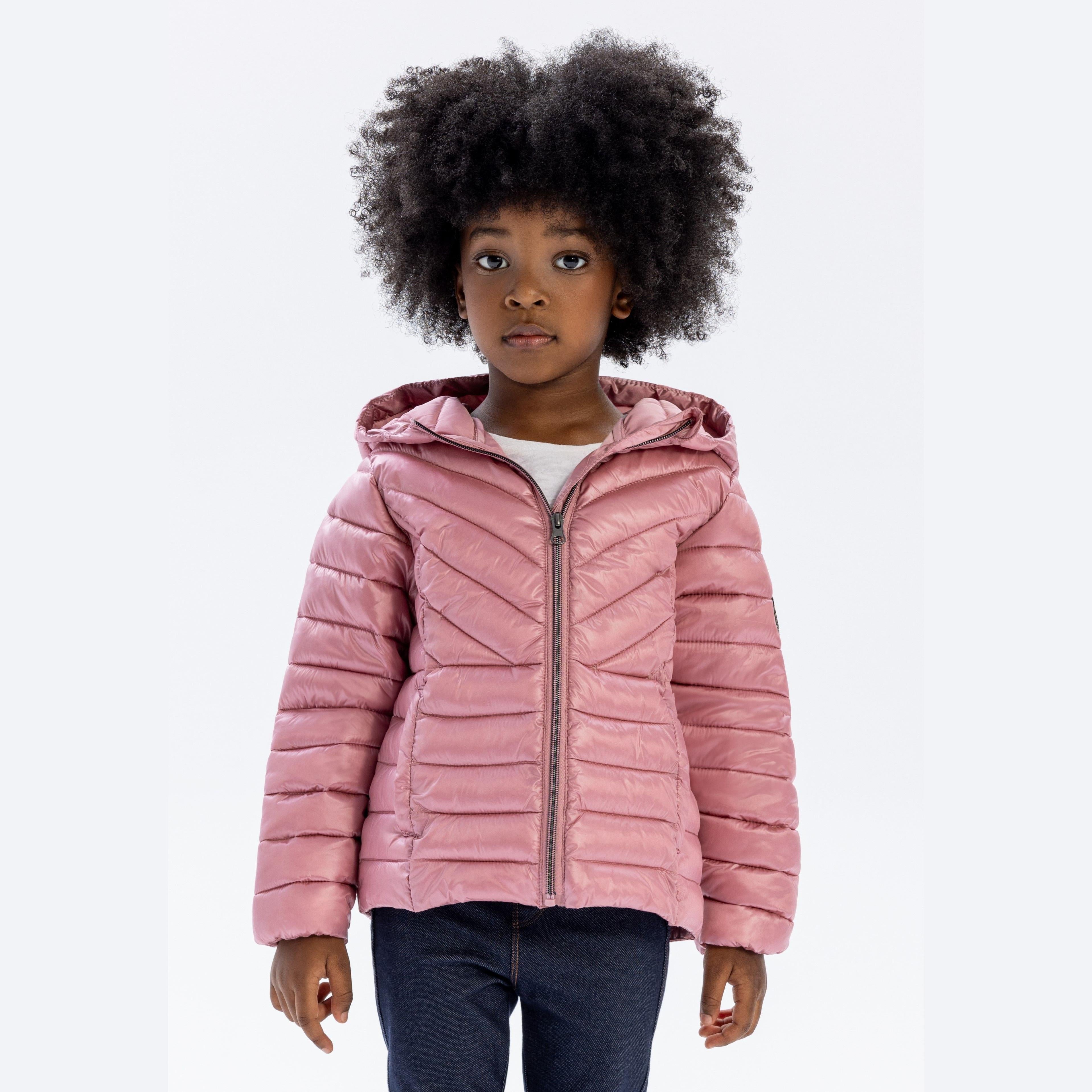 Young girl wearing pink quilted hooded jacket with zip closure, standing against white background