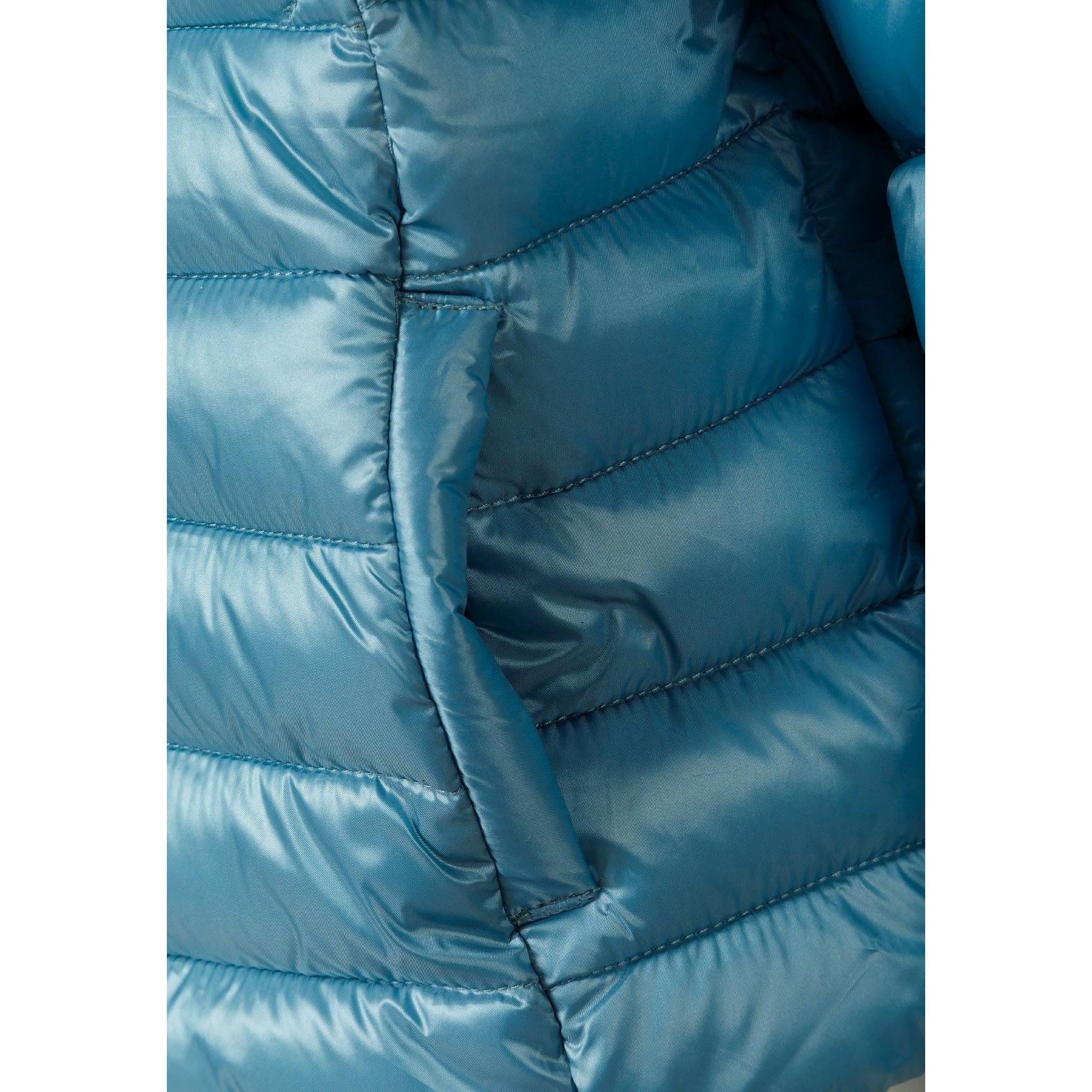 Close-up detail of circular embroidered patch with heart design on turquoise quilted fabric