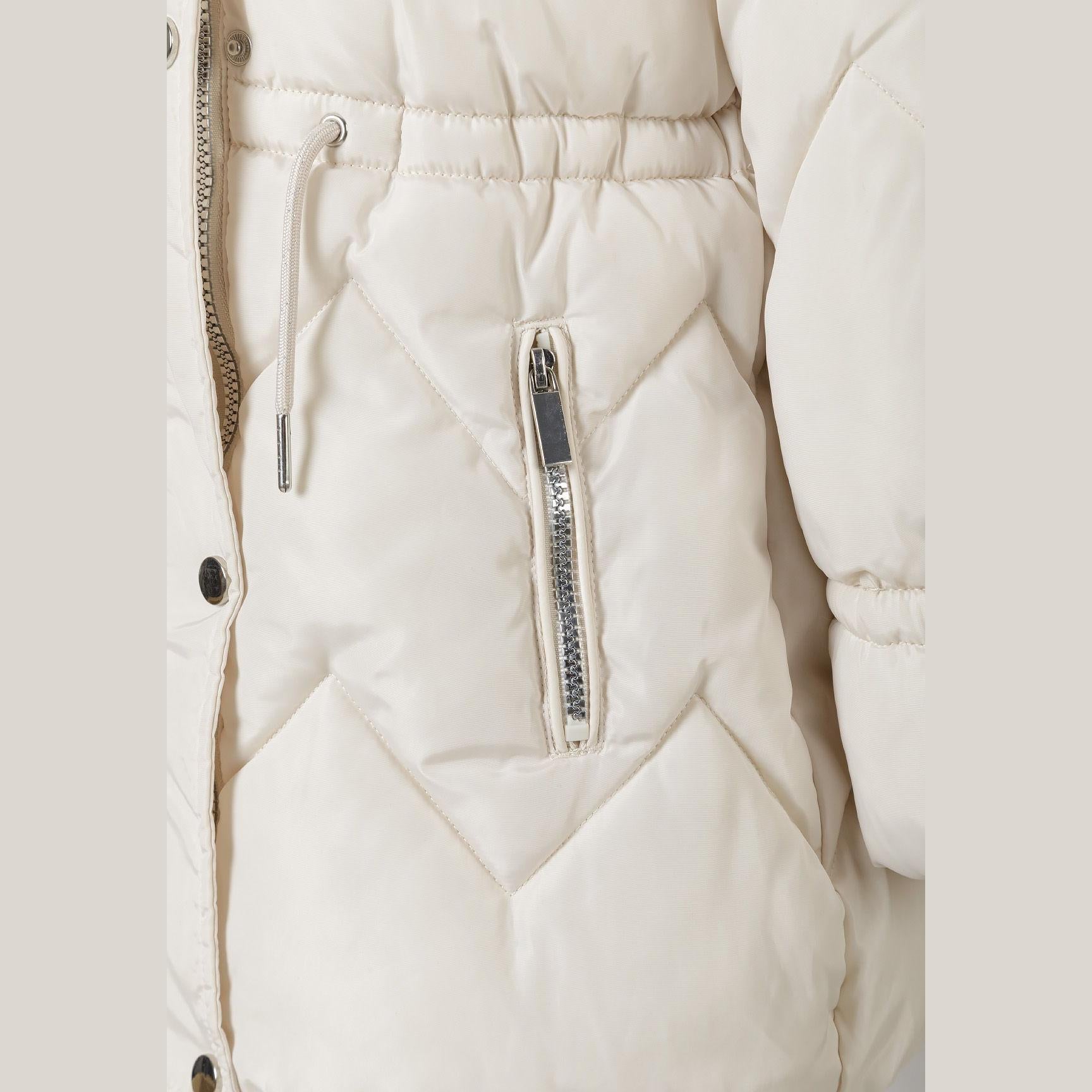 Close-up detail of cream quilted parka jacket showing diamond quilting pattern, faux fur hood trim texture and snap button closure on white background