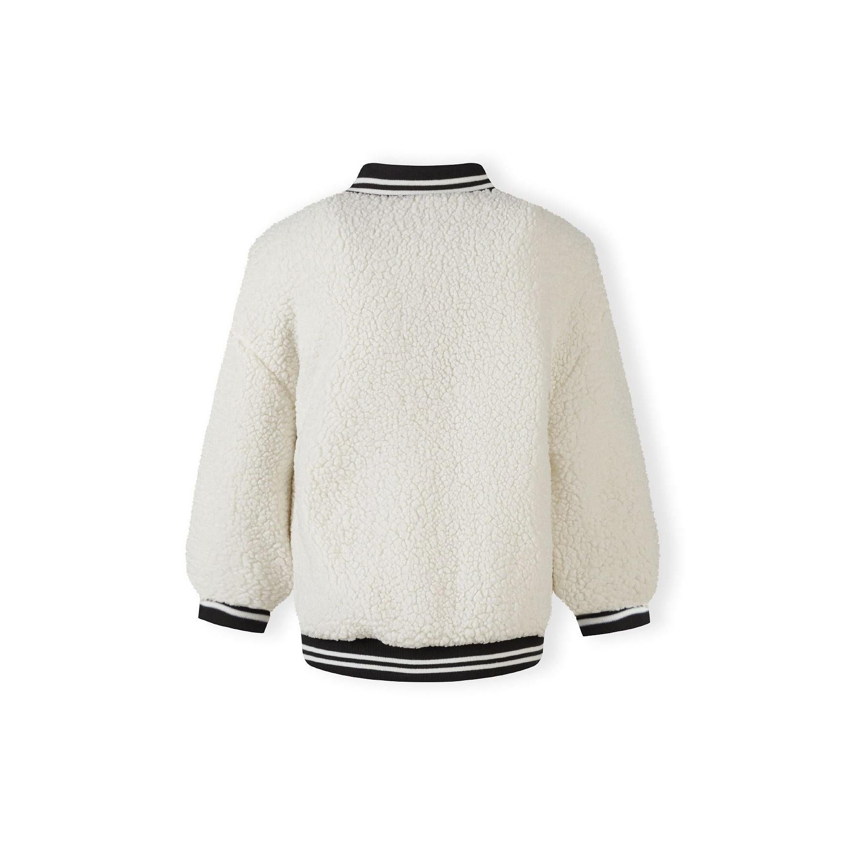 Close-up detail of embroidered letter M on cream borg fabric showing black outline stitching against textured surface