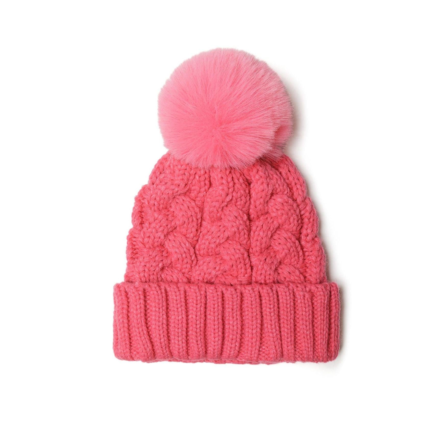 Close-up detail of pink cable knit texture and fluffy pom pom attachment on hat crown