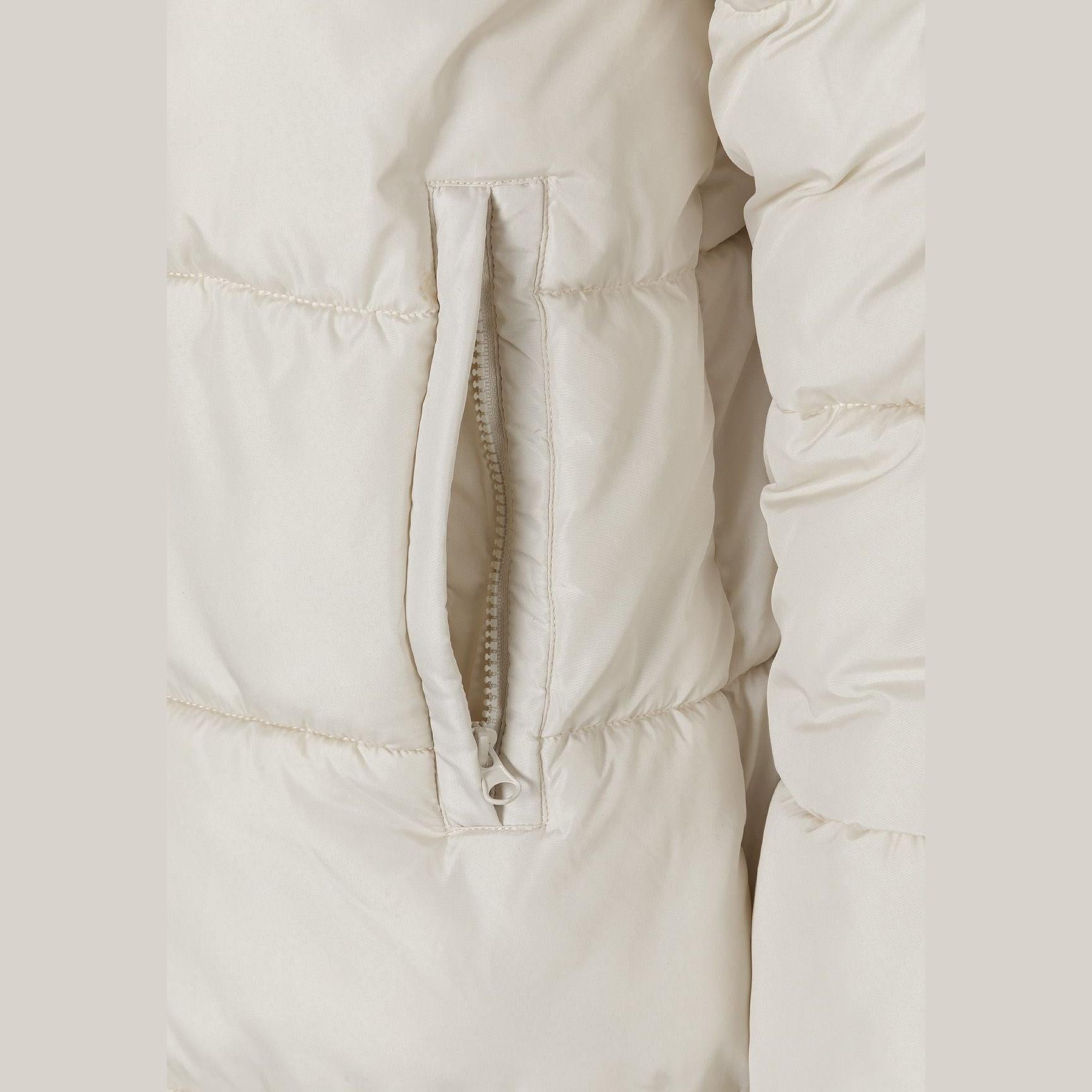 Close-up detail of cream puffer jacket showing quilted texture and zip pocket
