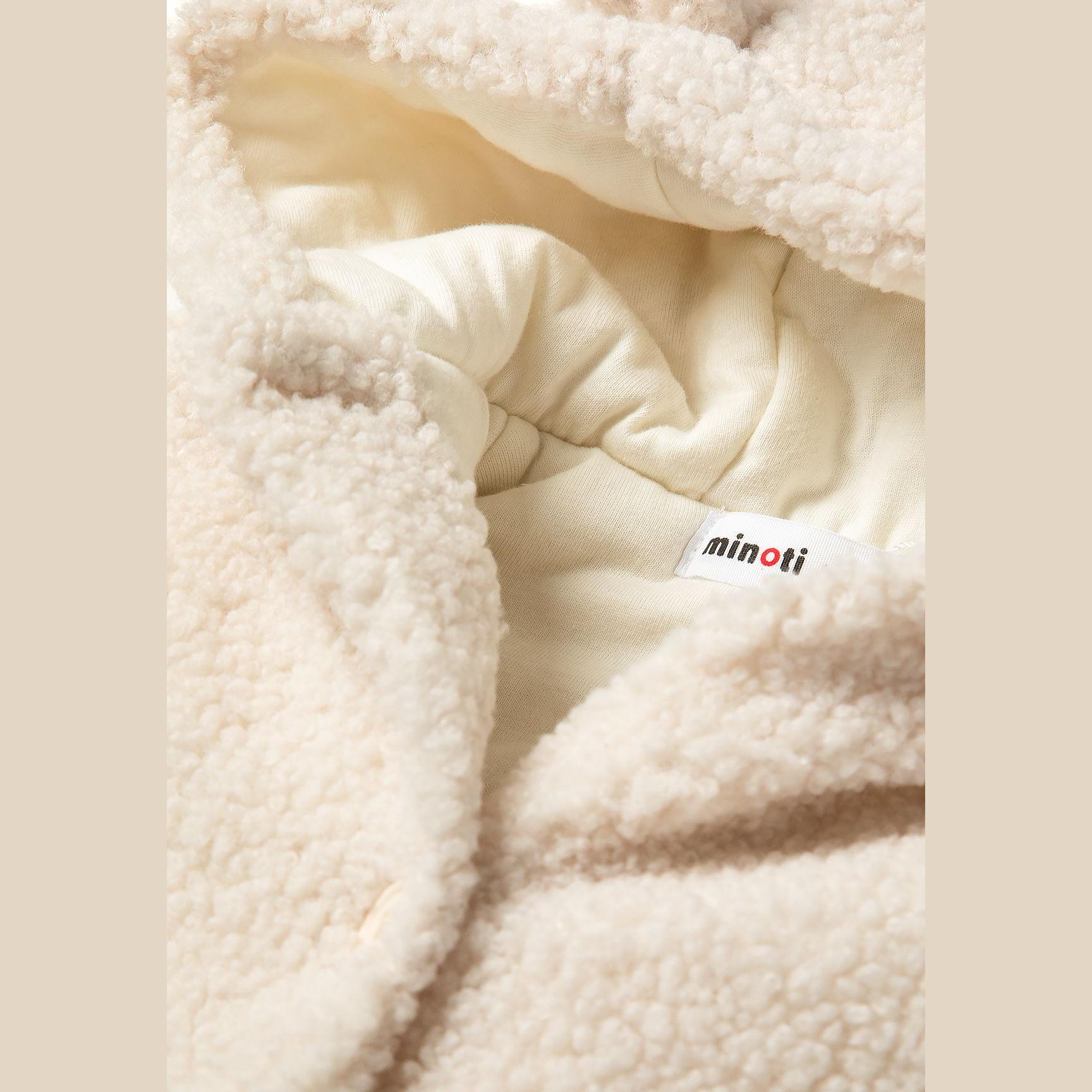 Close-up detail of cream teddy fabric texture with Minoti label visible on cream cotton lining
