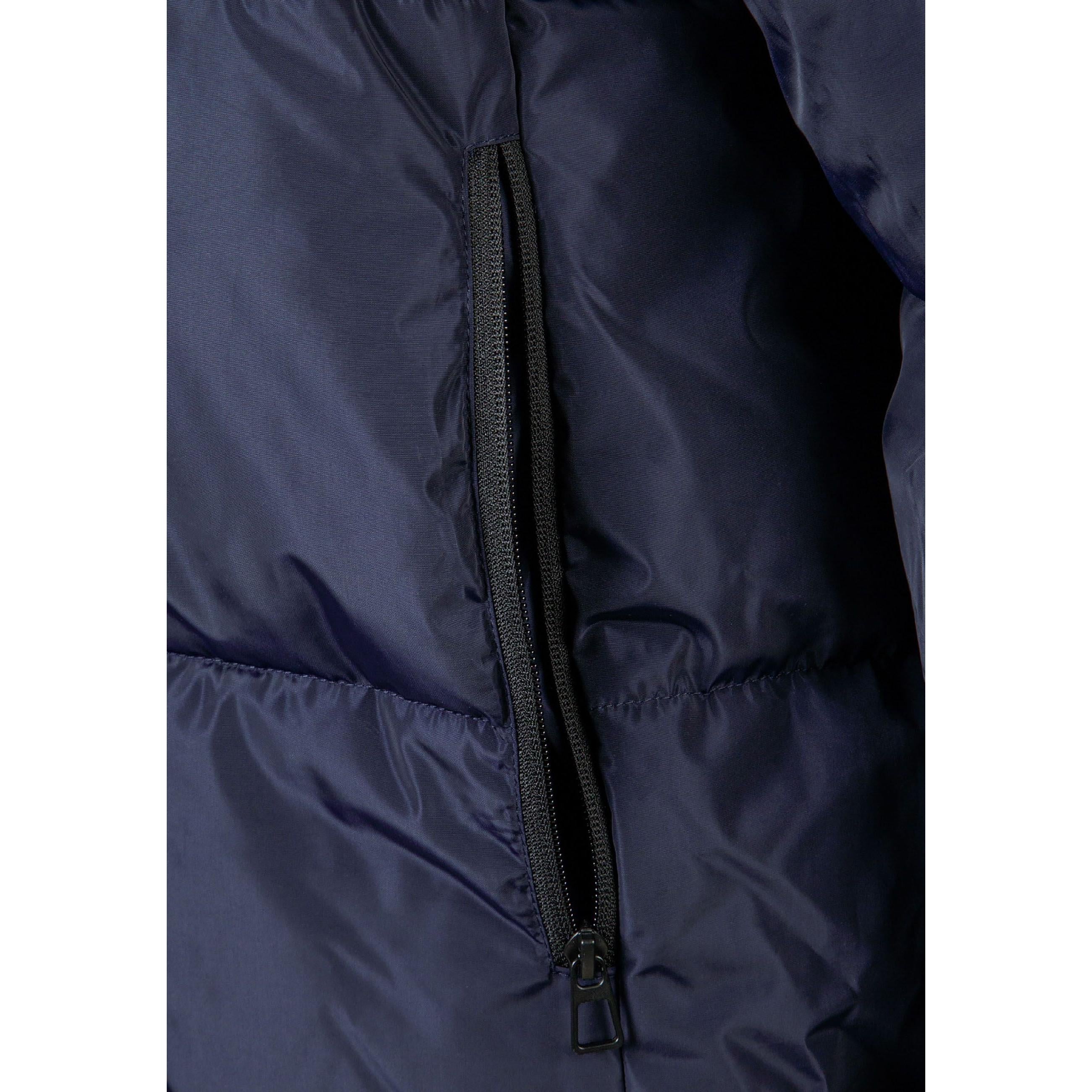 Close-up detail of navy quilted jacket showing zip fastening with black zipper pull on quilted fabric surface