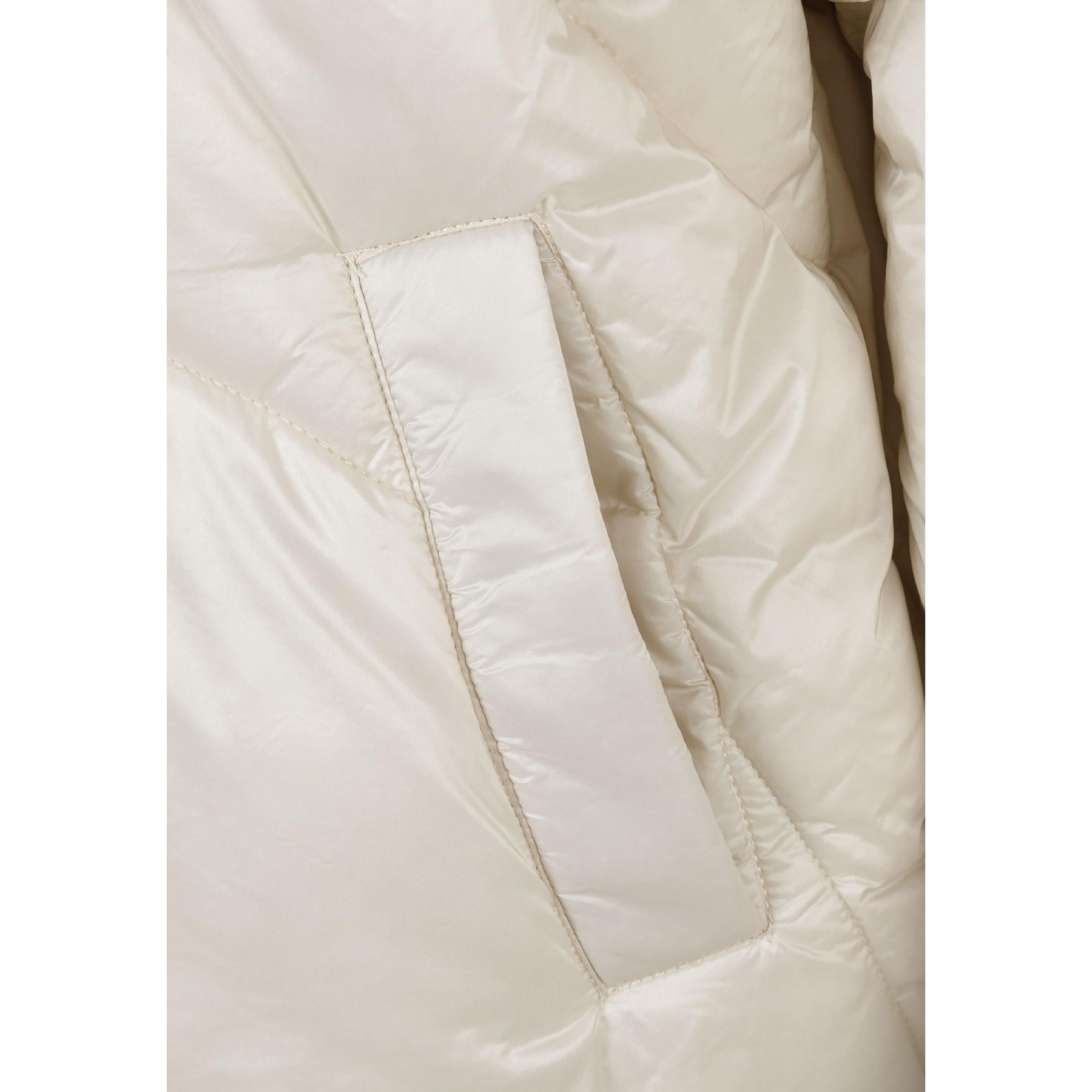 Close-up detail of cream puffer jacket showing quilted stitching pattern and side pocket on white background