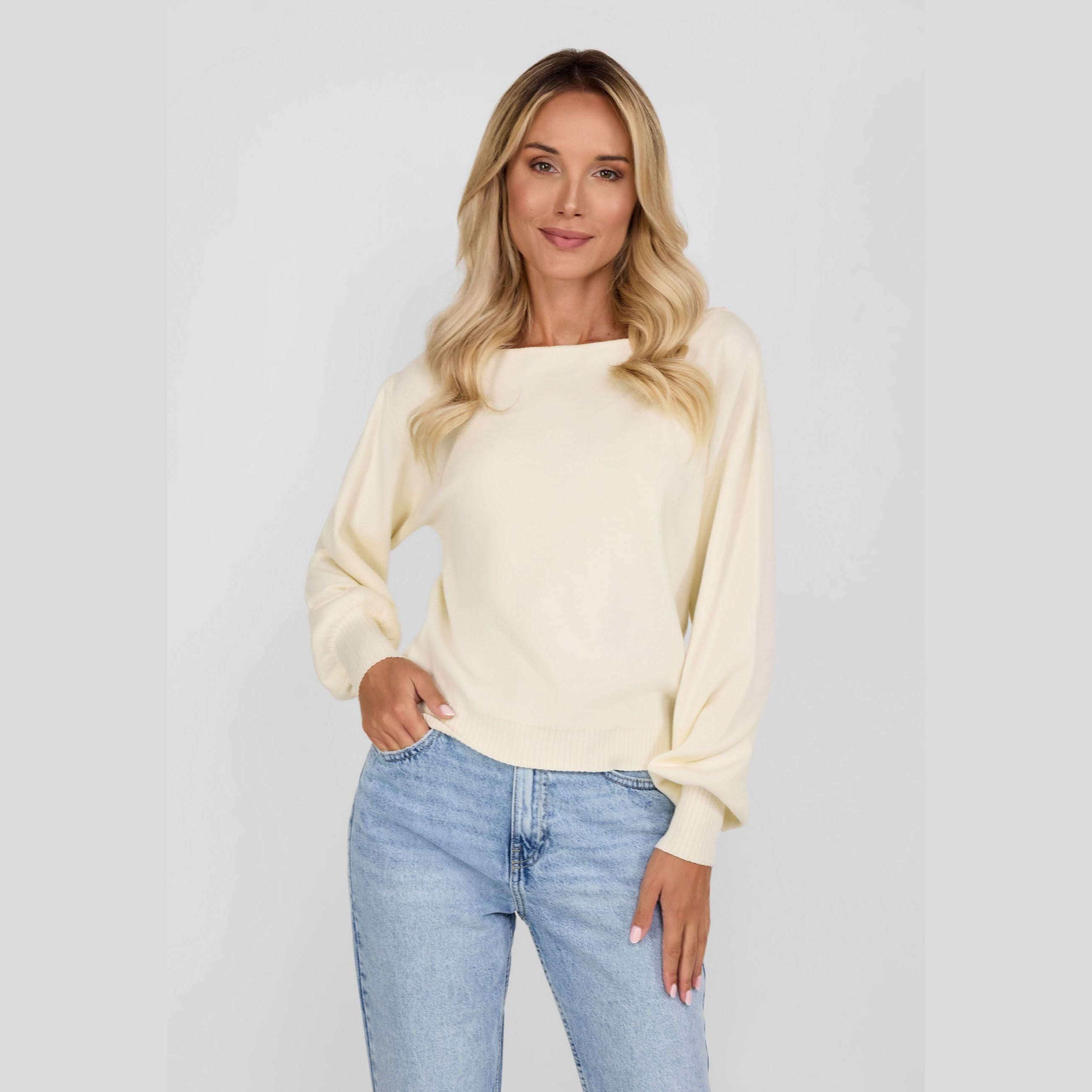 Model wearing cream boat neck jumper with blue jeans against white background, front view showing relaxed fit and elegant neckline