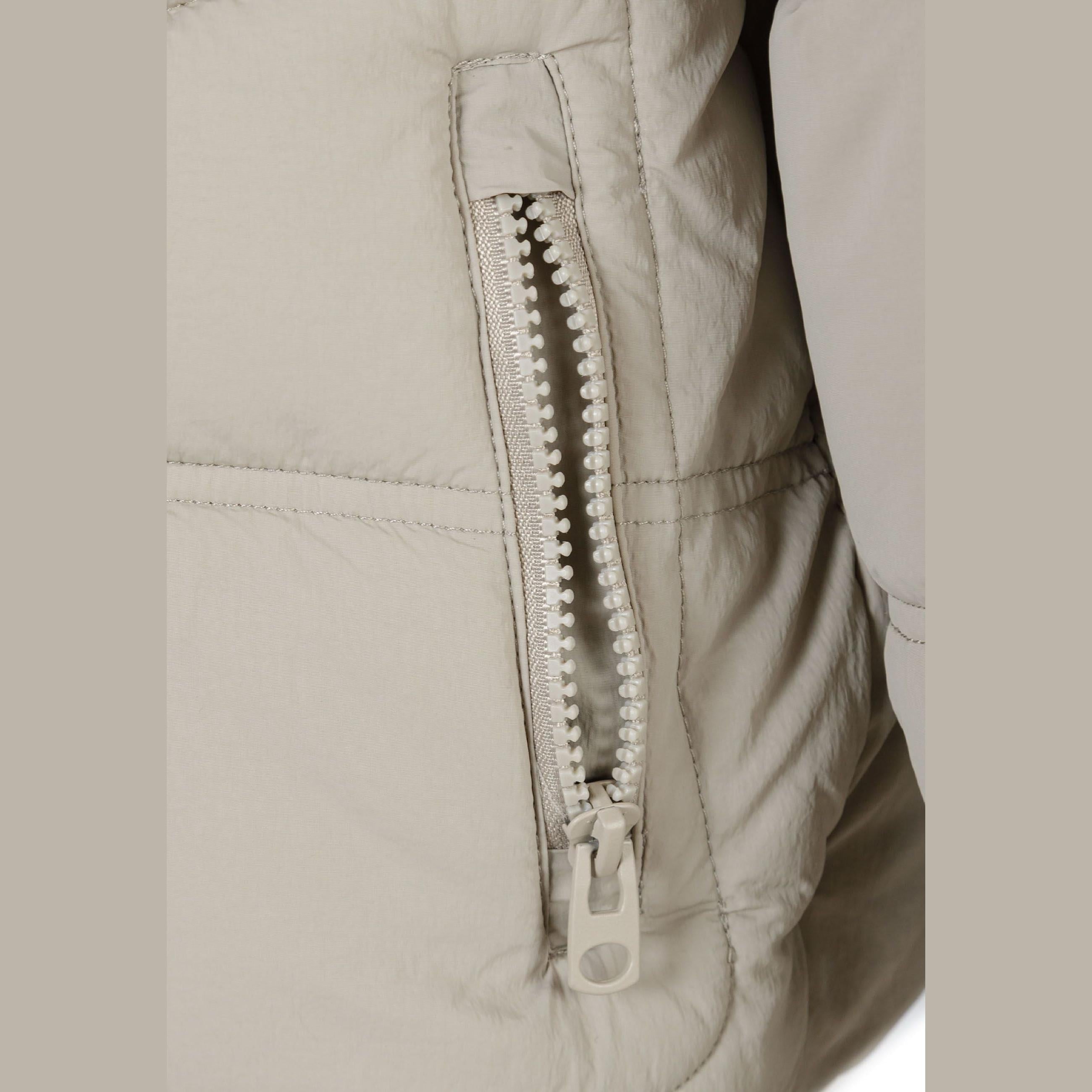 Close-up detail of black rubber performance patch on grey quilted jacket sleeve with outdoor since 1997 text