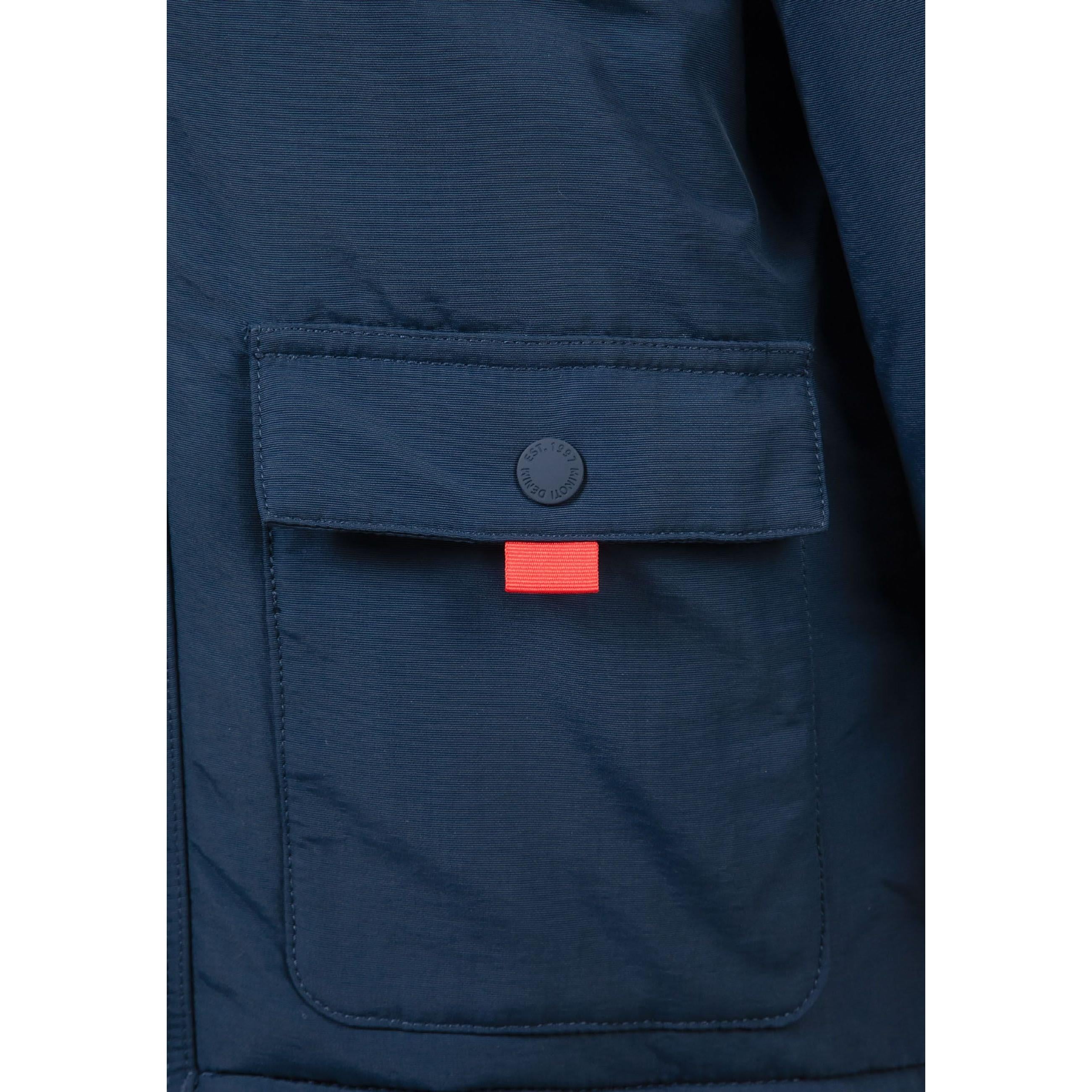 Close-up detail of navy parka pocket with button closure and red accent tab showing fabric texture