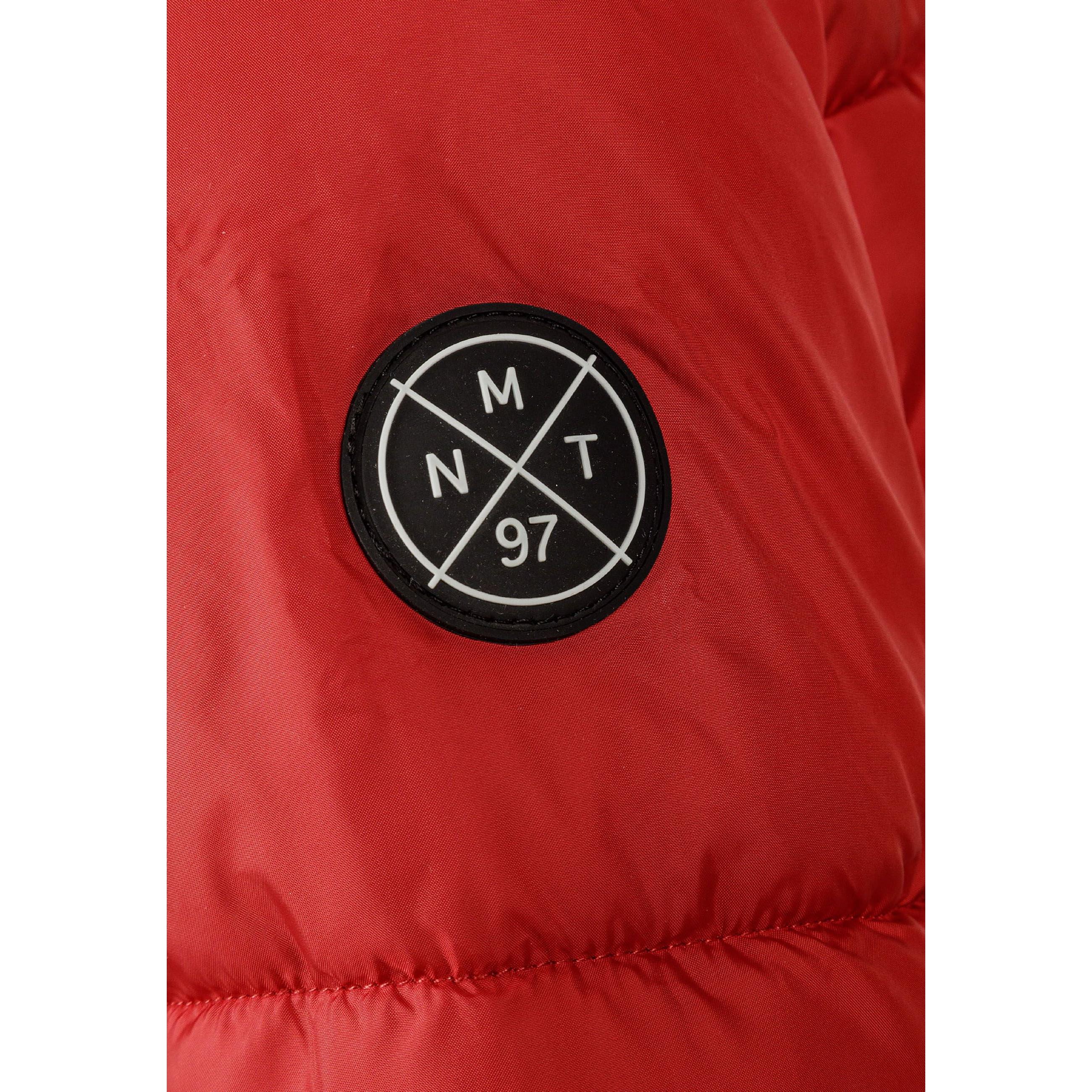 Close-up detail of black circular logo patch with white crossed lines and letters M N T 97 on red jacket sleeve