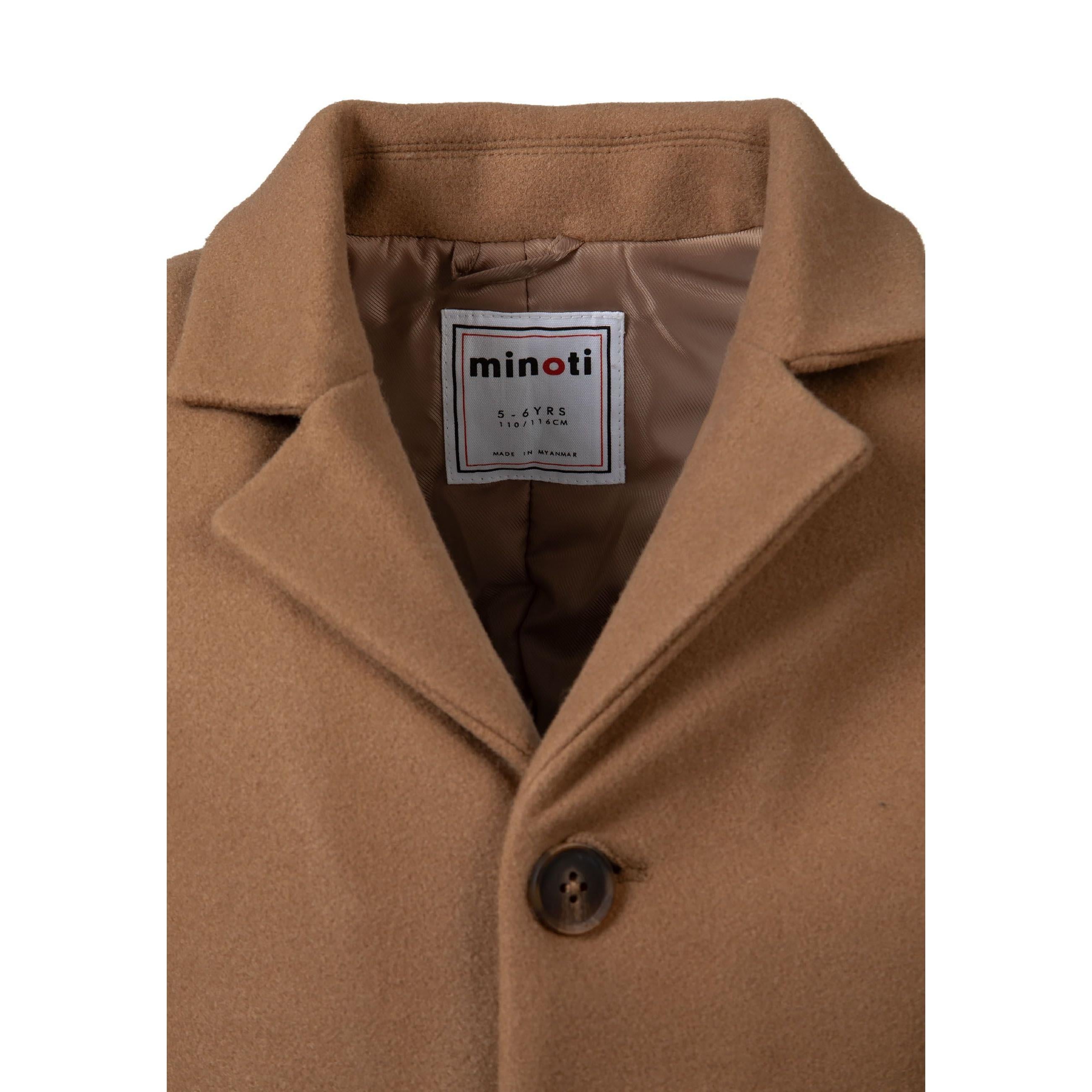 Close-up detail of beige coat fabric showing hidden seam pocket construction and smooth texture