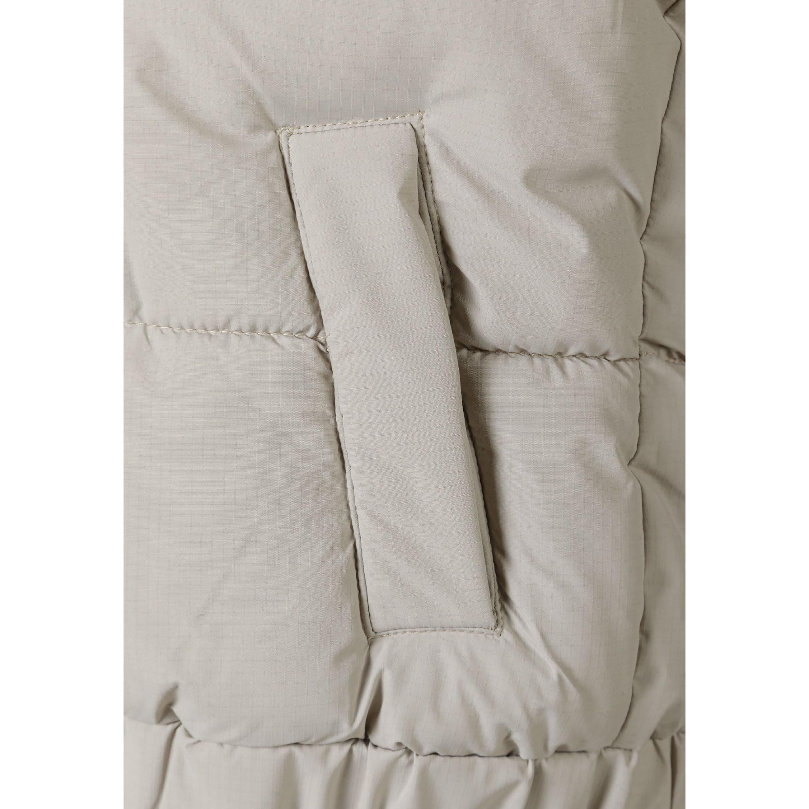 Close-up detail of grey padded gilet showing zip pocket construction and quilted fabric texture