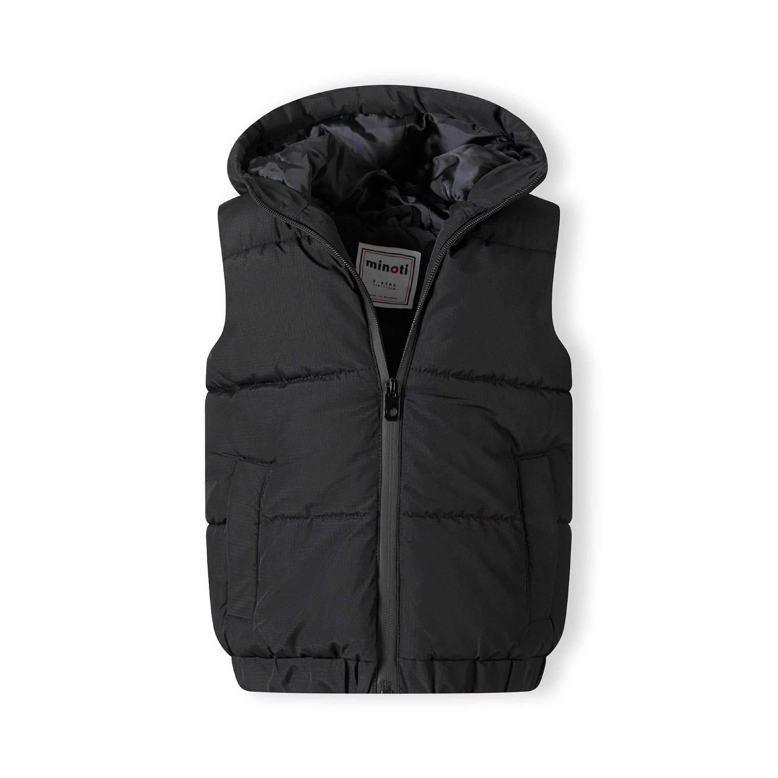 Close-up detail of black gilet showing zip pocket construction and padded quilted fabric texture