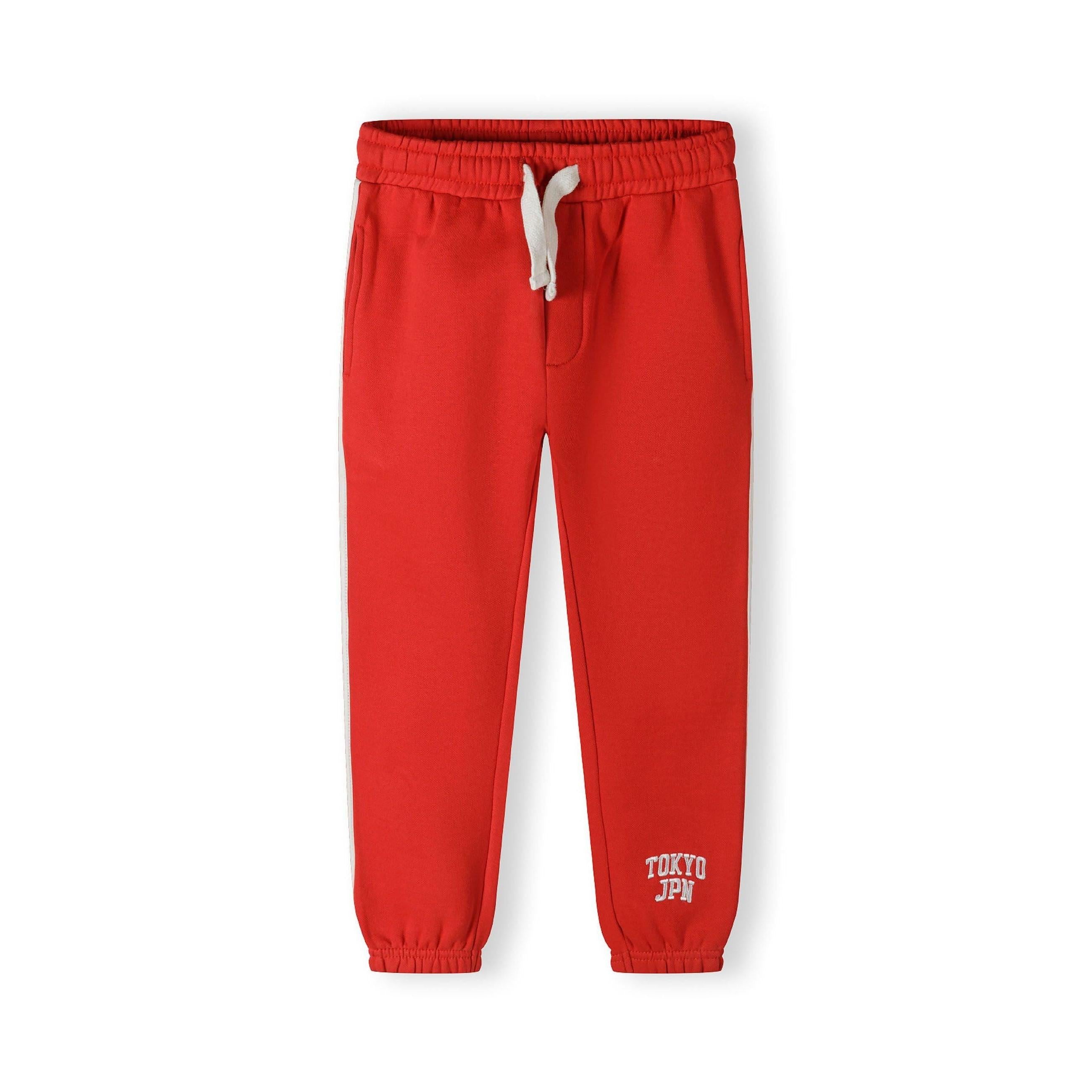 Close-up detail of red joggers showing white drawstring ties and front pocket construction