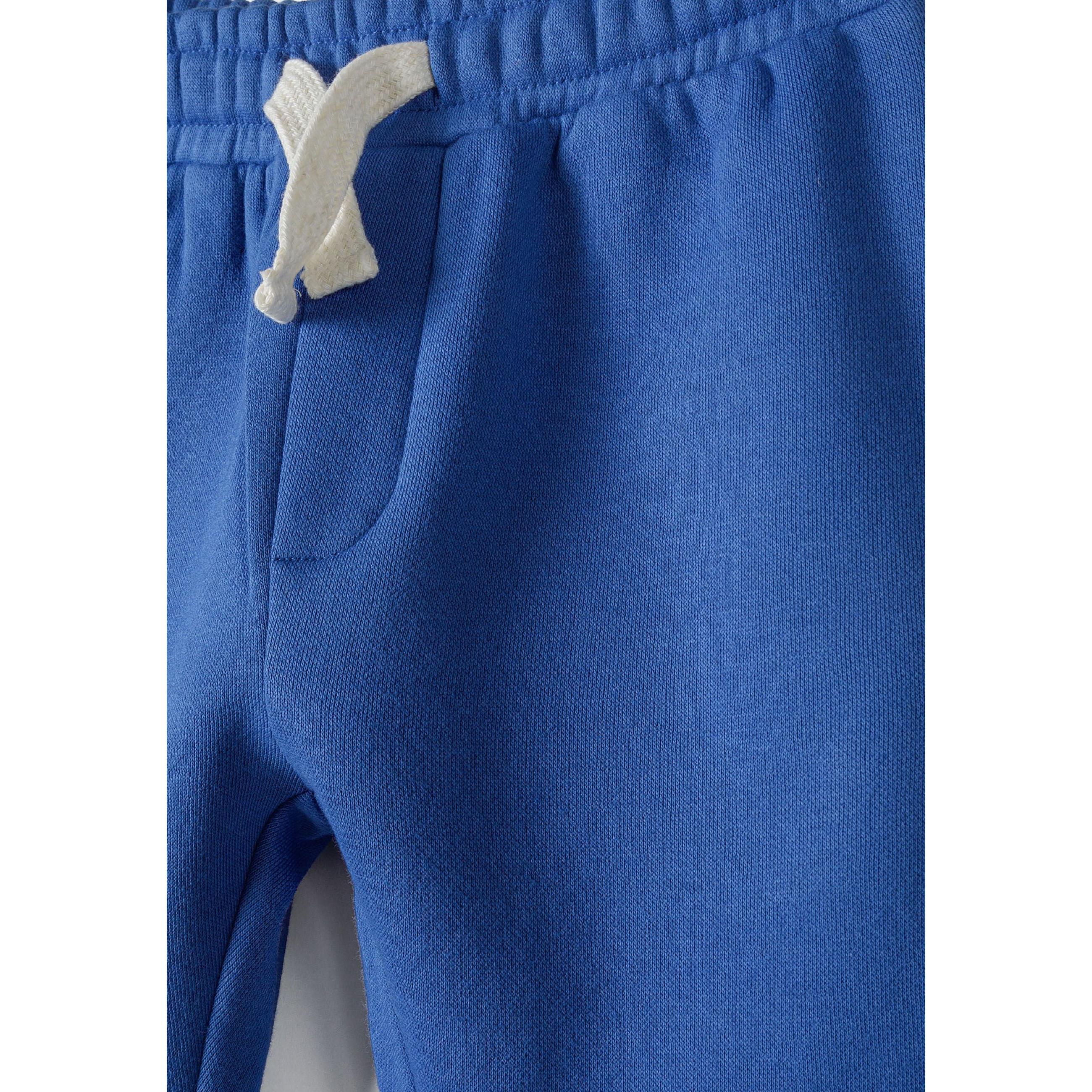 Close-up detail of cobalt blue joggers showing elasticated waistband with white drawstring ties