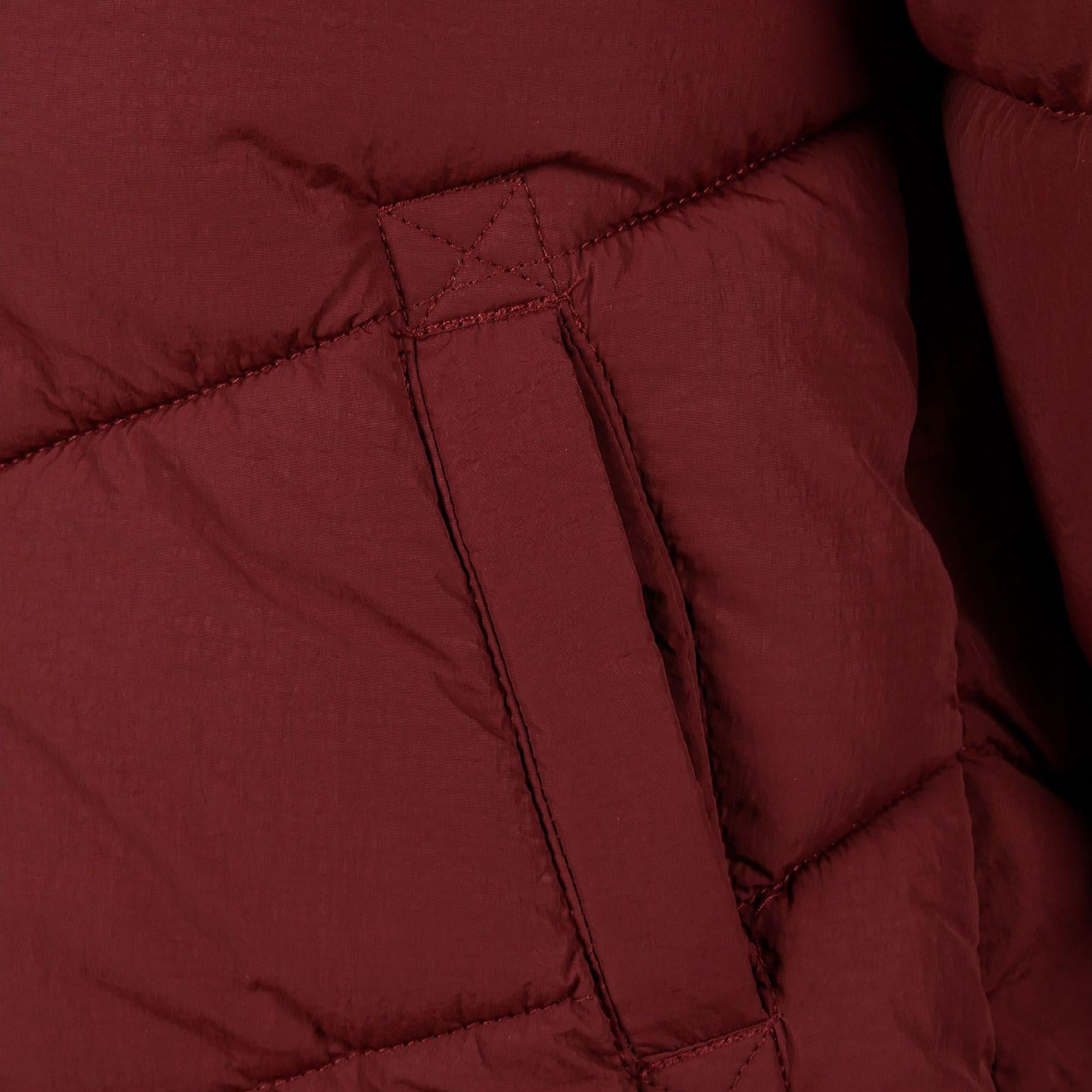 Close-up detail of burgundy quilted fabric showing diagonal stitching pattern and front pocket with matching trim